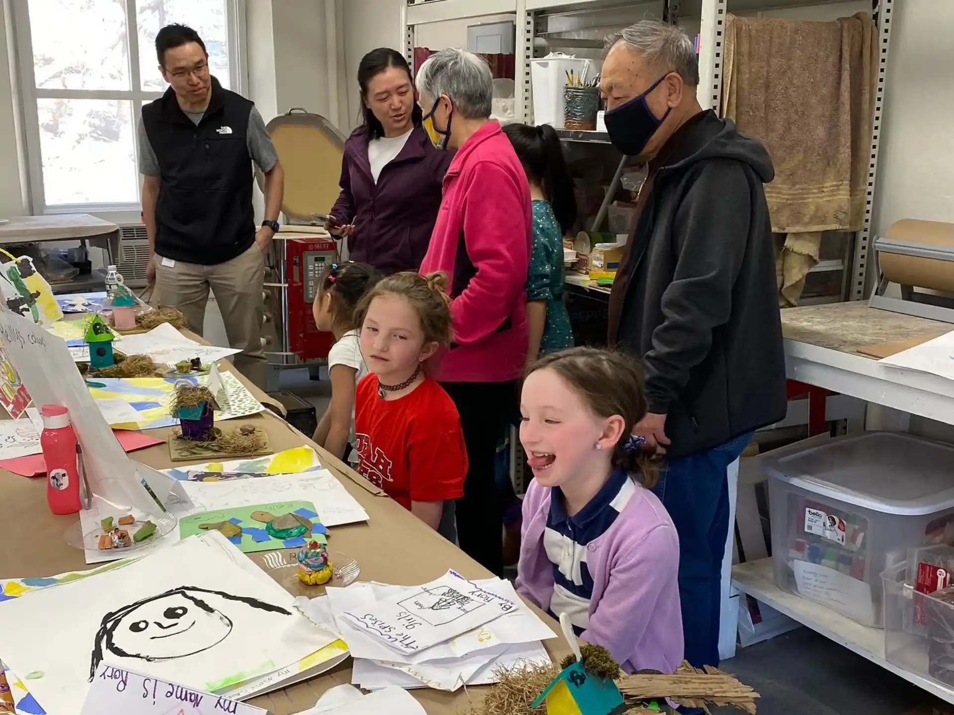 a group of people standing around a table with a cake on it