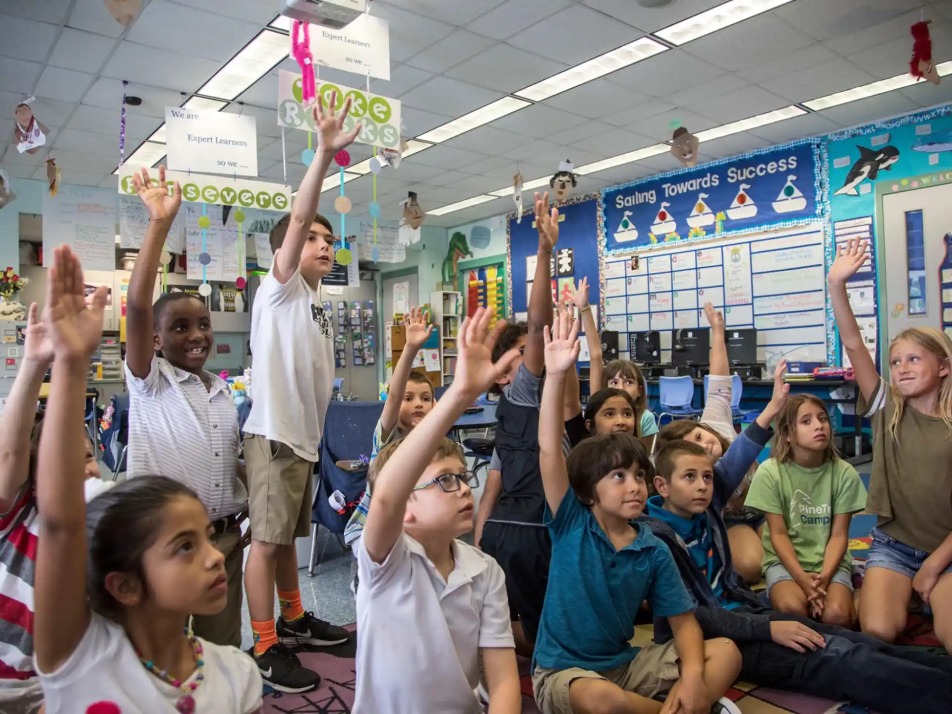 a group of children raising their hands
