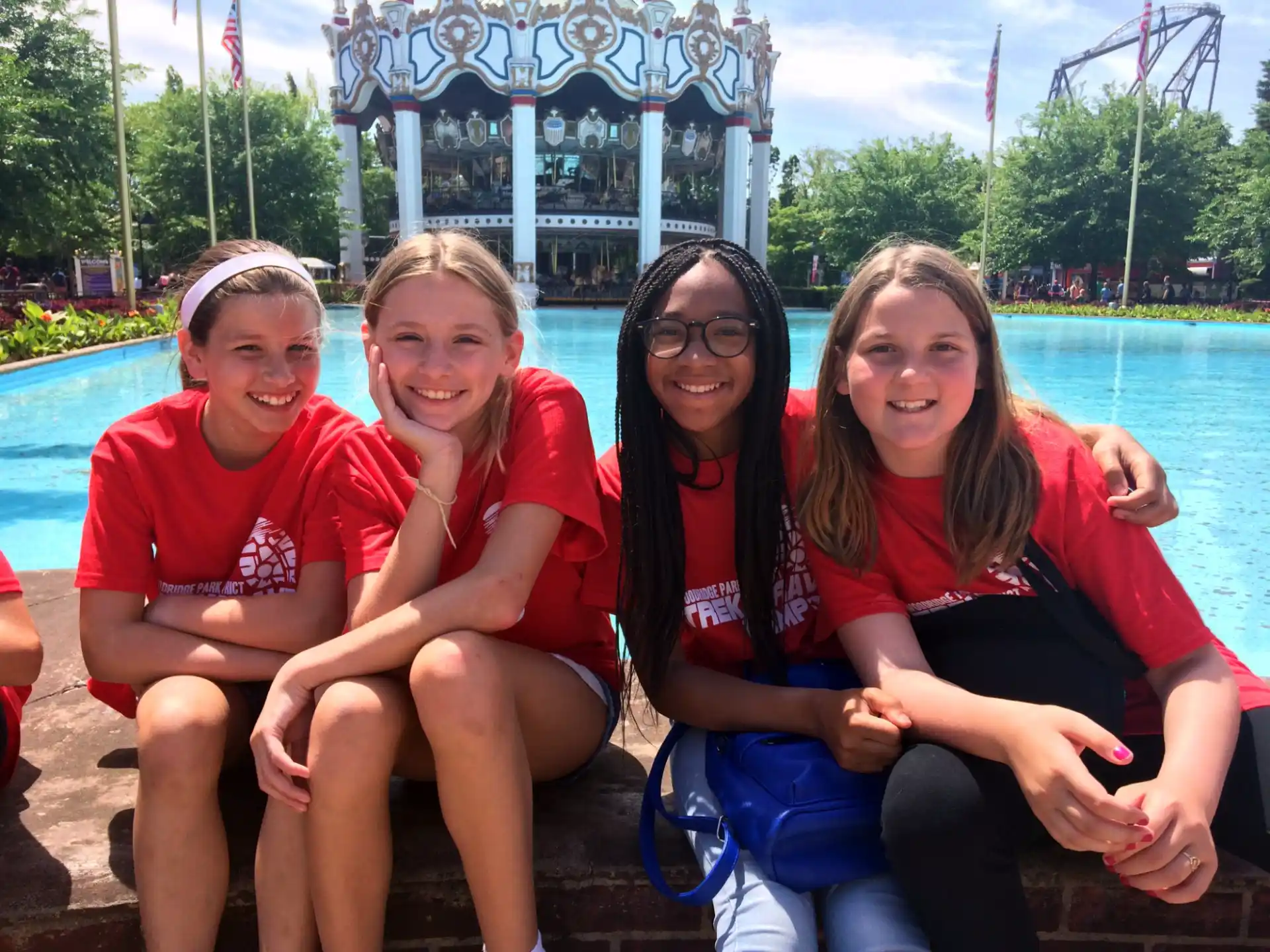 a group of girls sitting on a bench in front of a water park