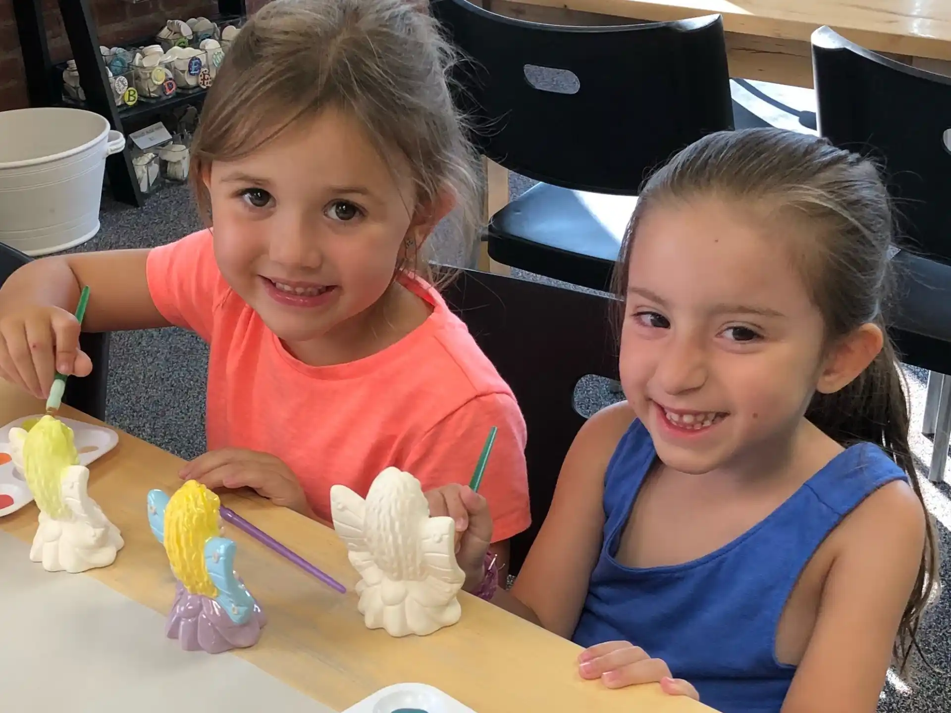 a couple of girls sitting at a table with toys