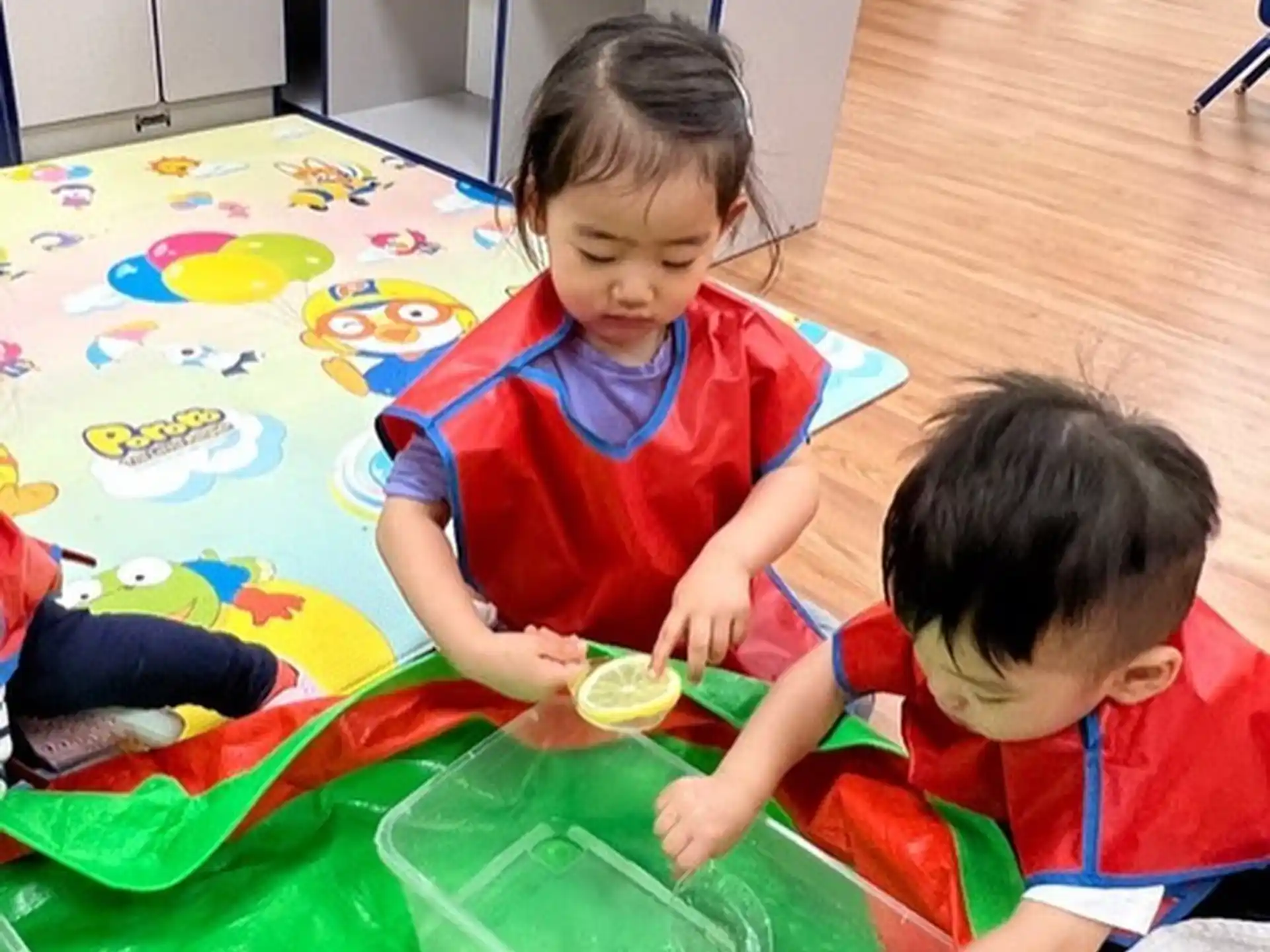 a couple of kids playing on a colorful mat