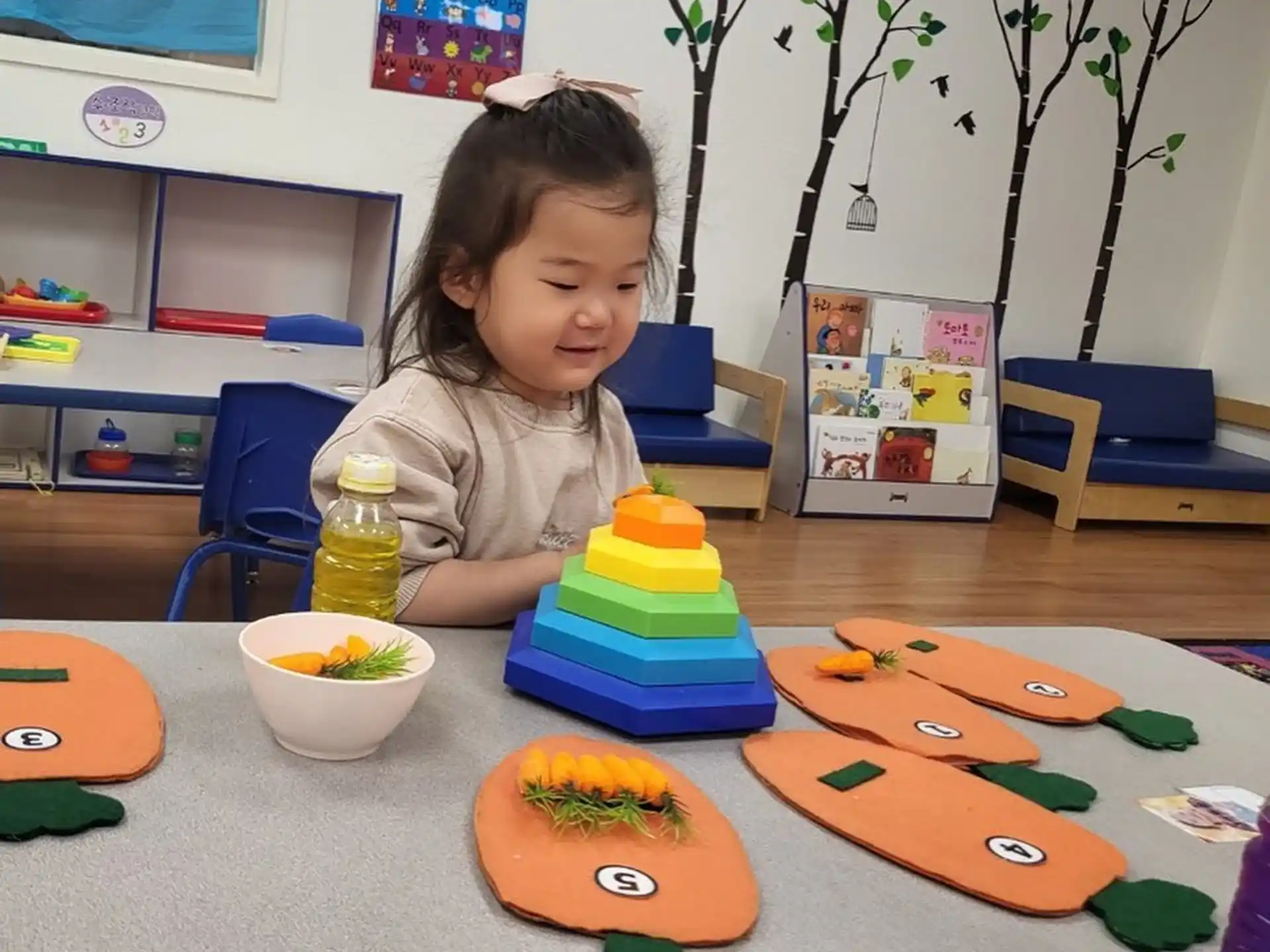 a girl sitting at a table with toys and a plant