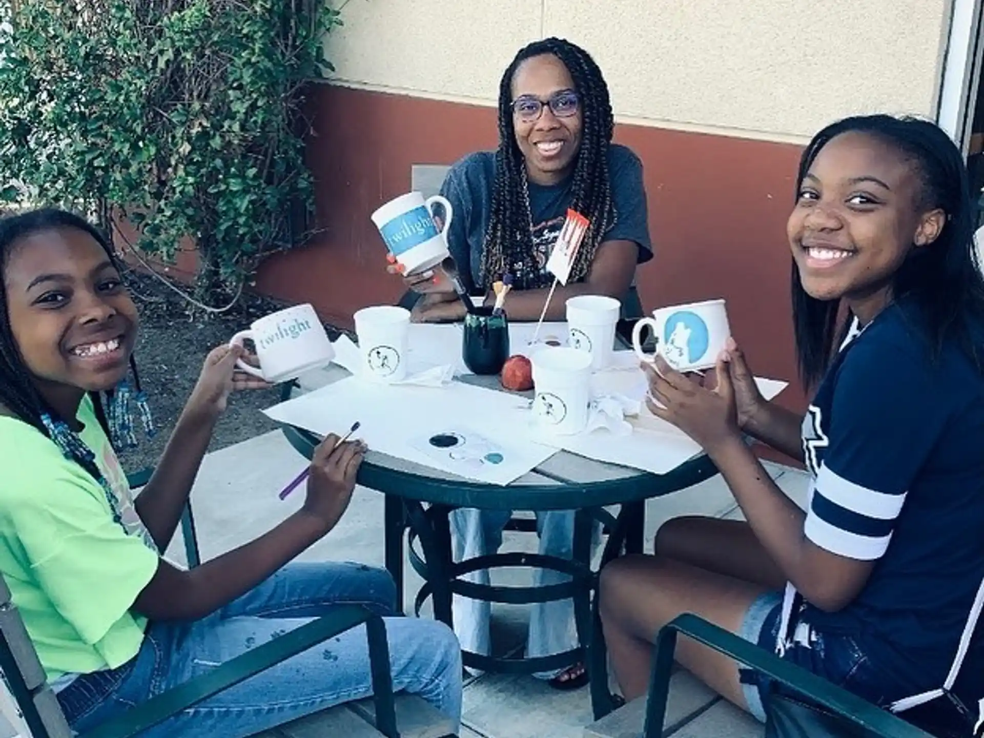 a group of women sitting at a table with coffee cups and a plant