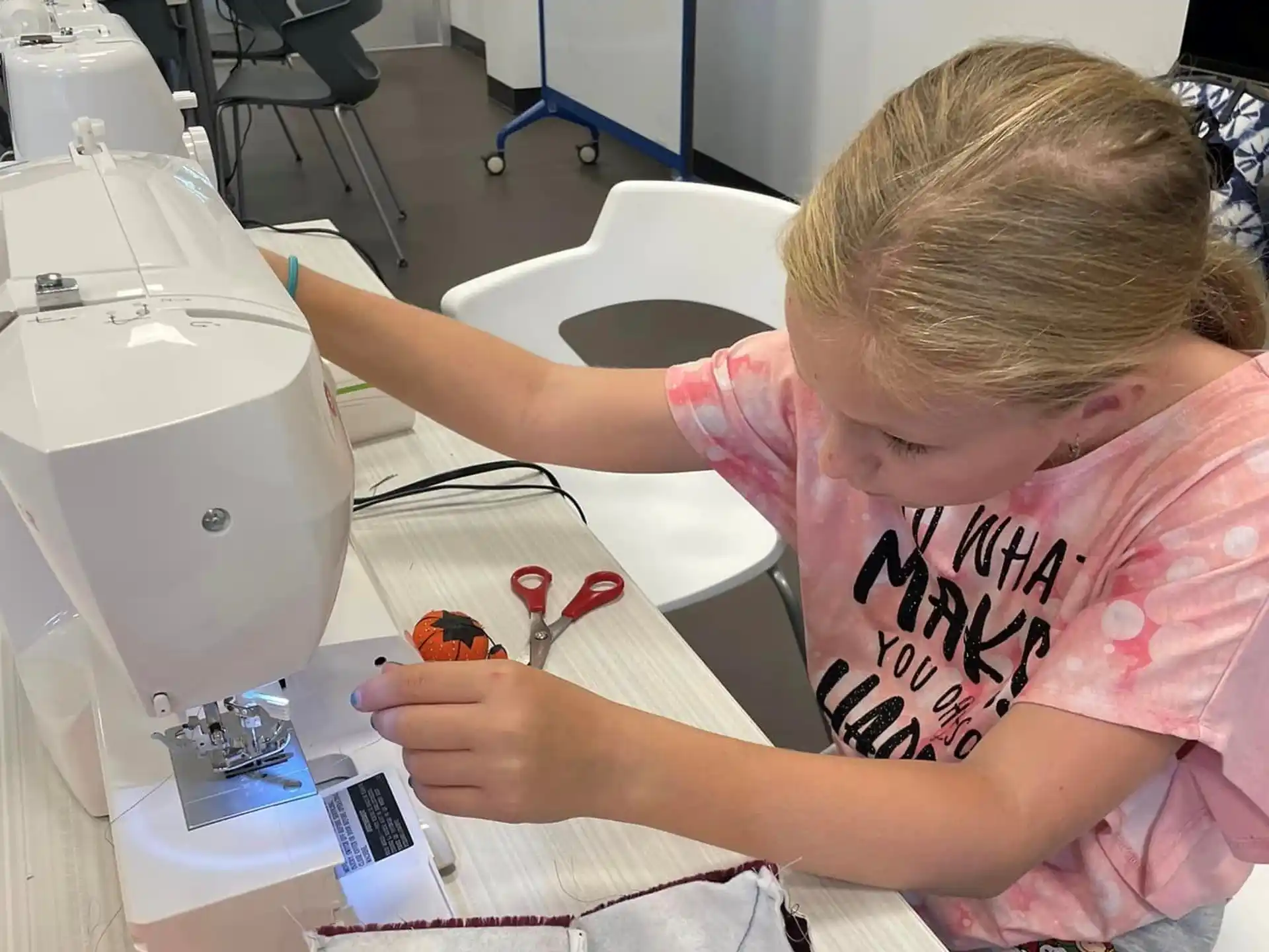 a young girl using a sewing machine