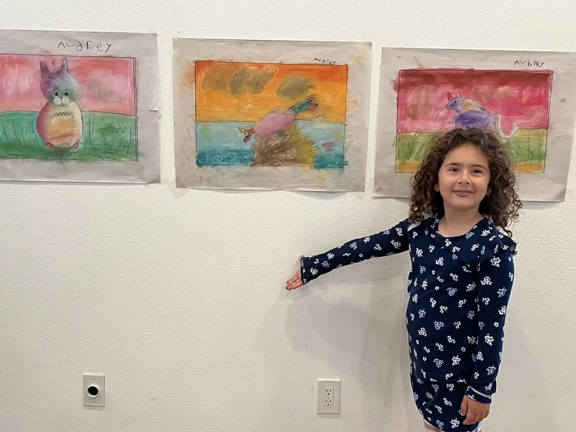 a girl standing in front of a wall with pictures on it
