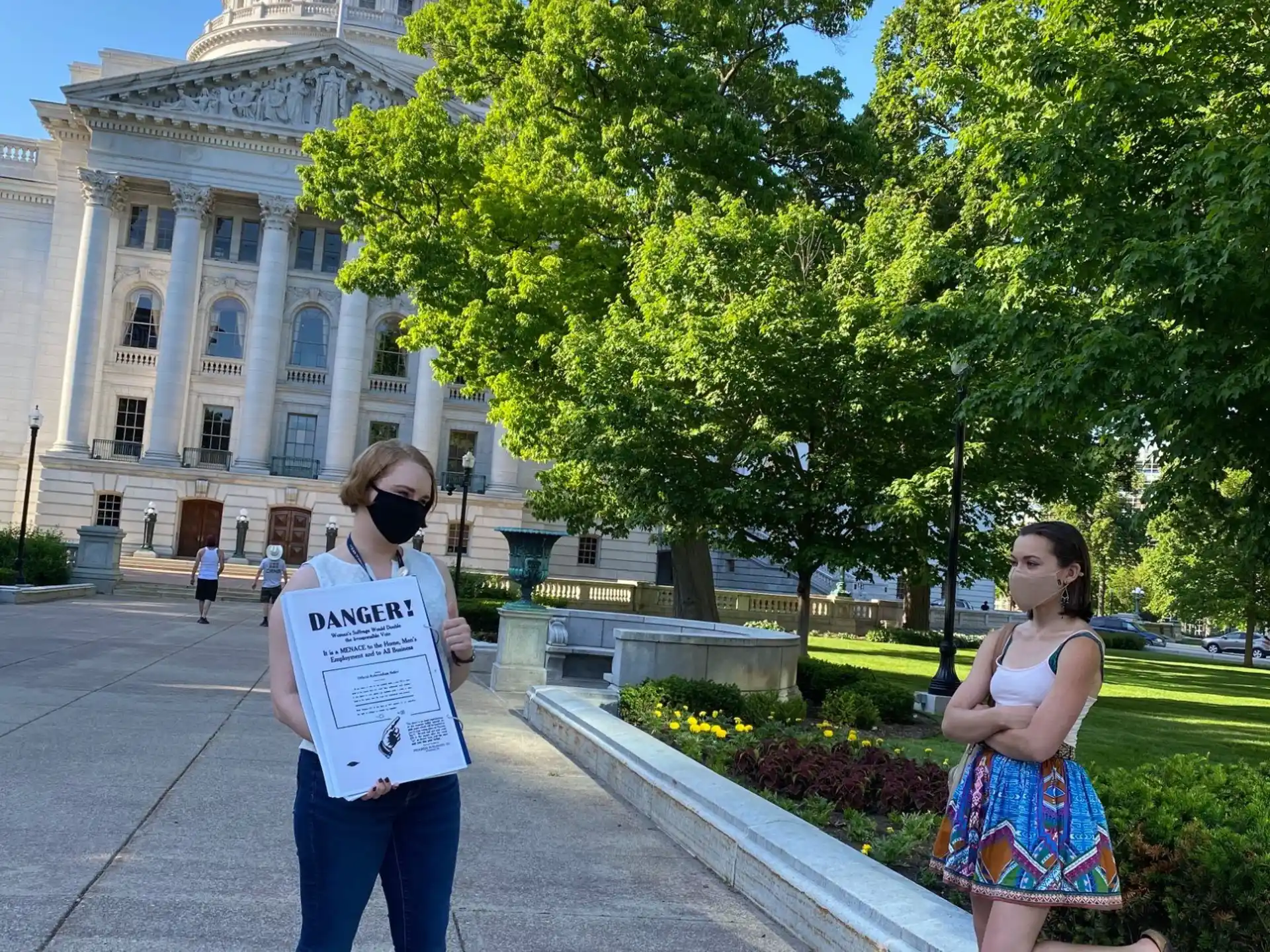 a person holding a sign next to a person sitting on a bench