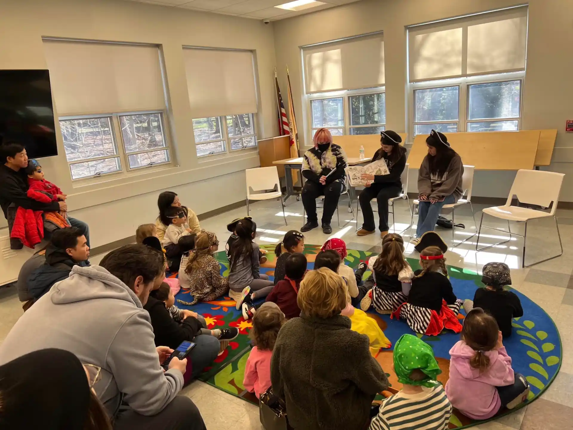 a group of people sitting in a room with a person playing a guitar