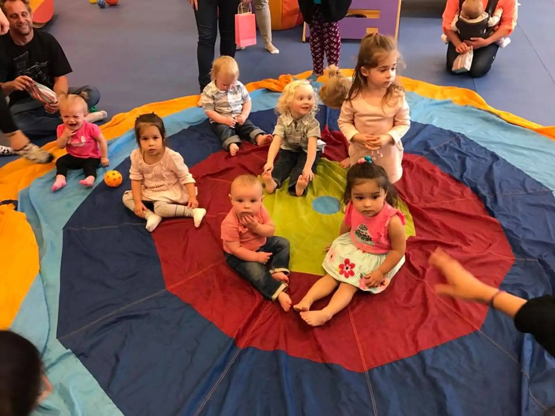 a group of children sitting on a red and yellow mat