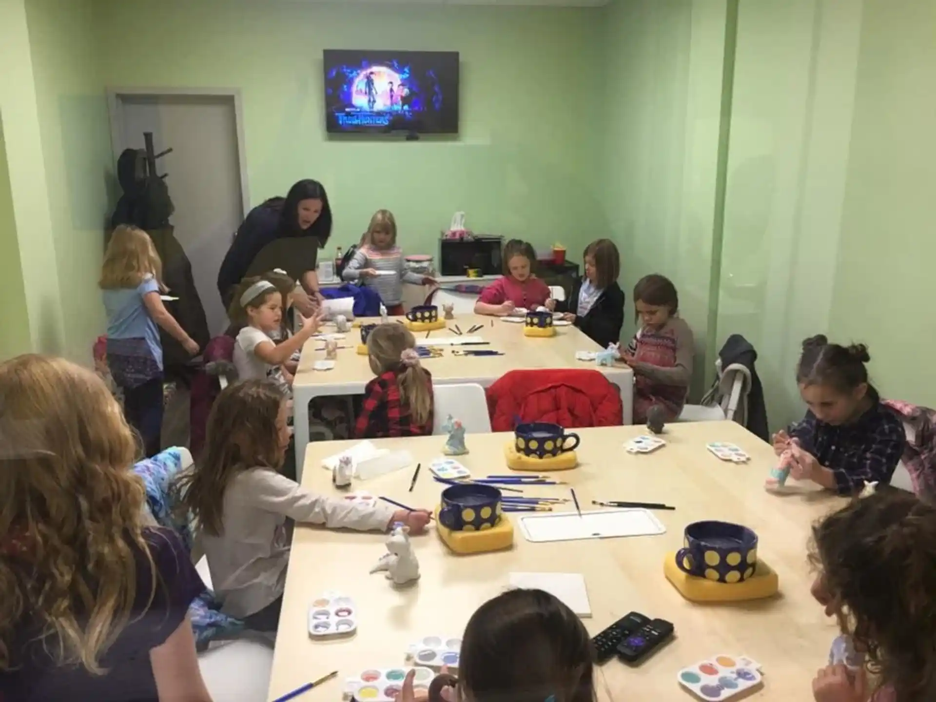 a group of children sitting at a table watching a television