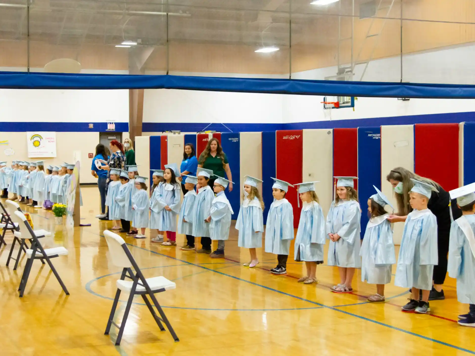 a group of children in white gowns and caps standing in a room