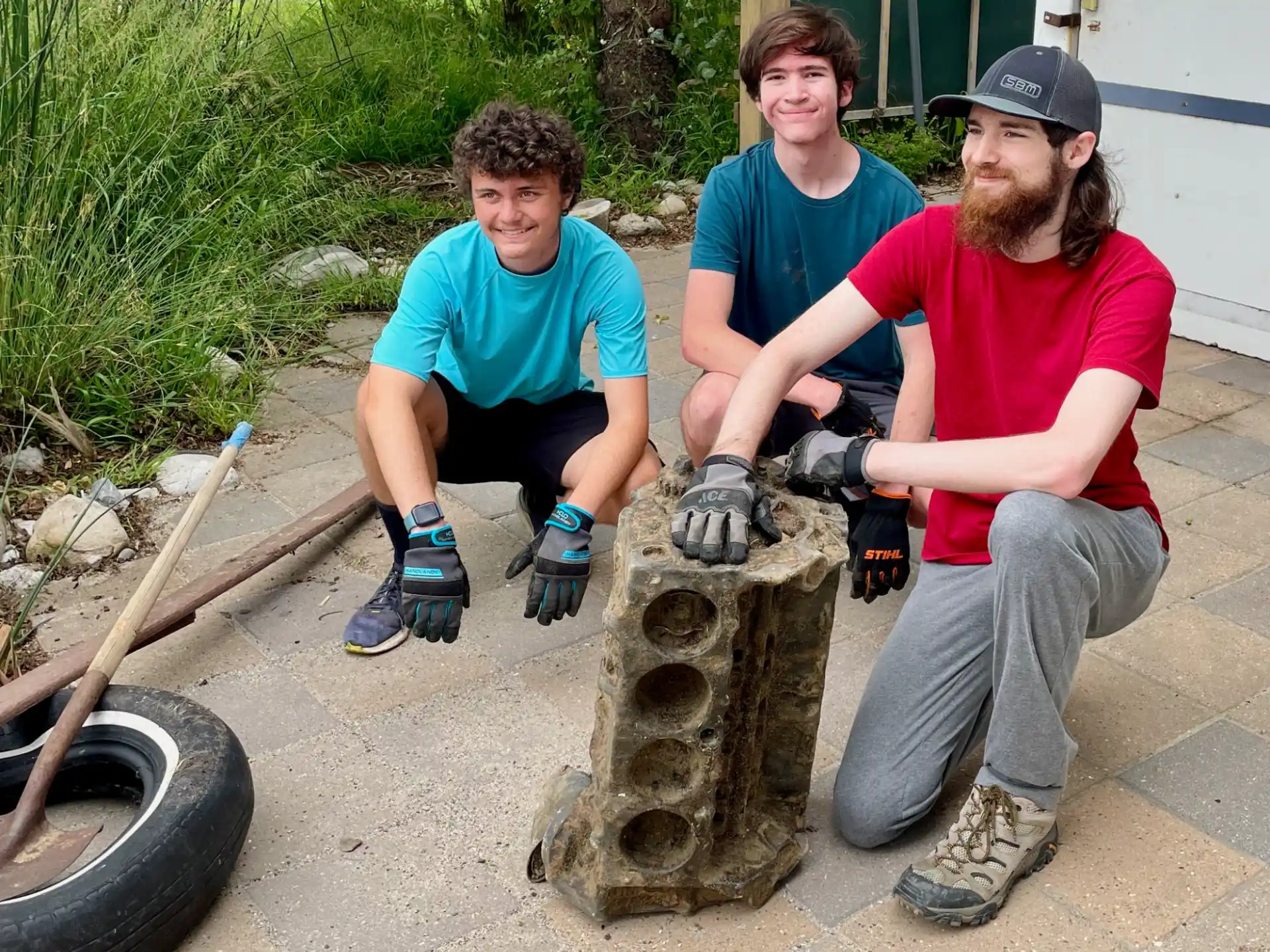 a group of people sitting on a stump with a tire and a wheel