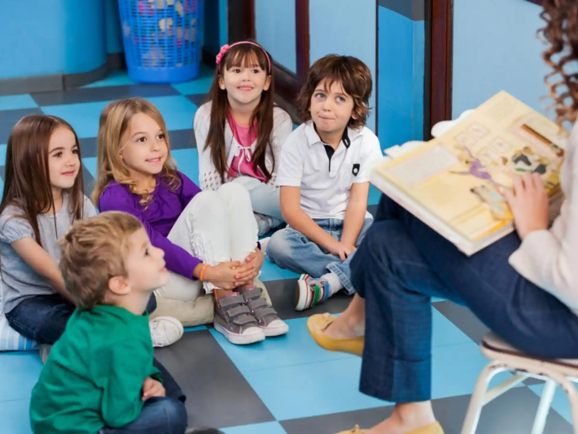a group of children sitting on the floor reading a book