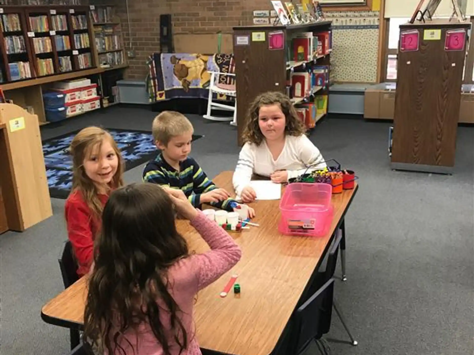 a group of children sitting at a table in a library