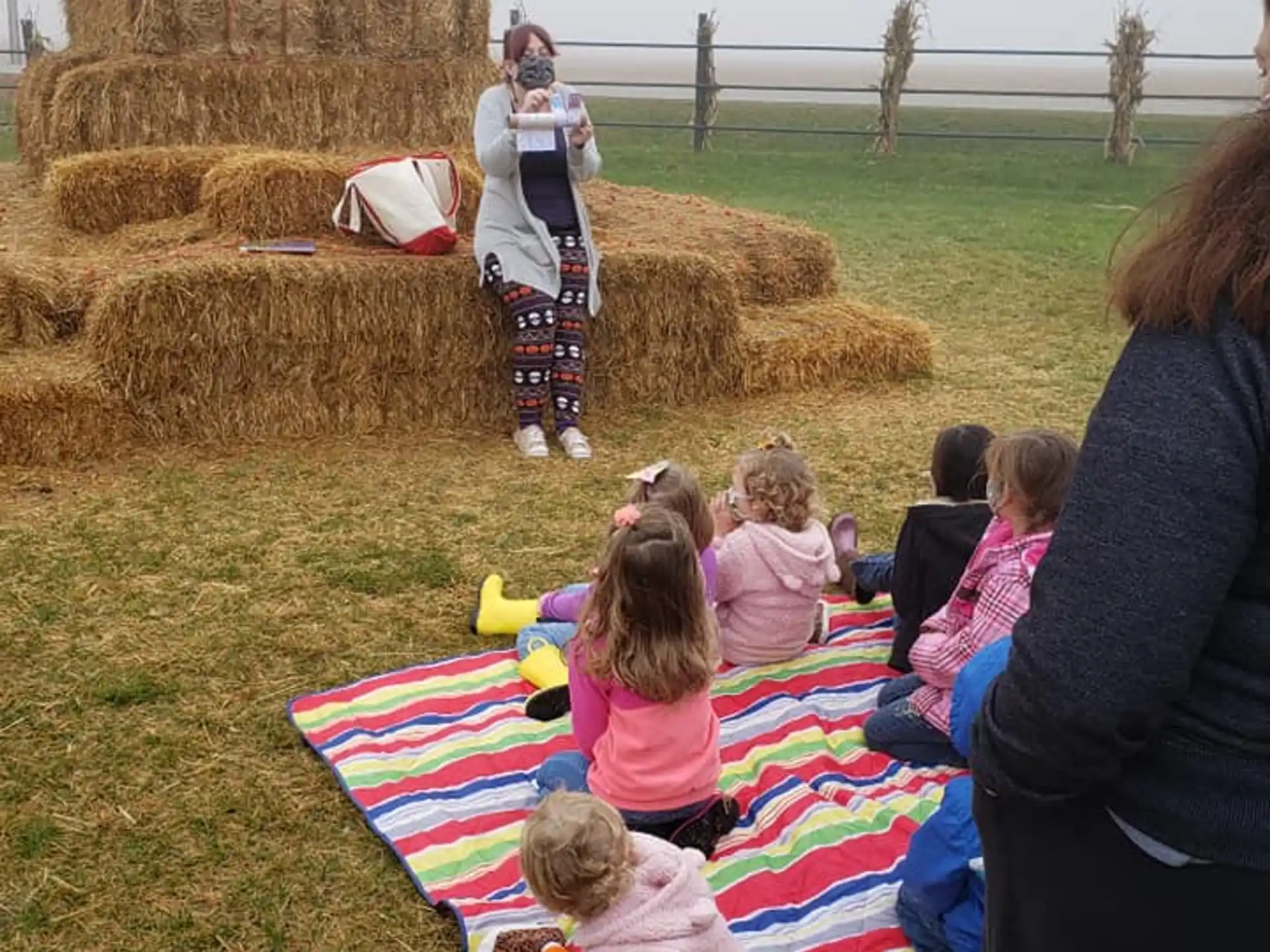 a group of children sitting on a blanket in a grassy field