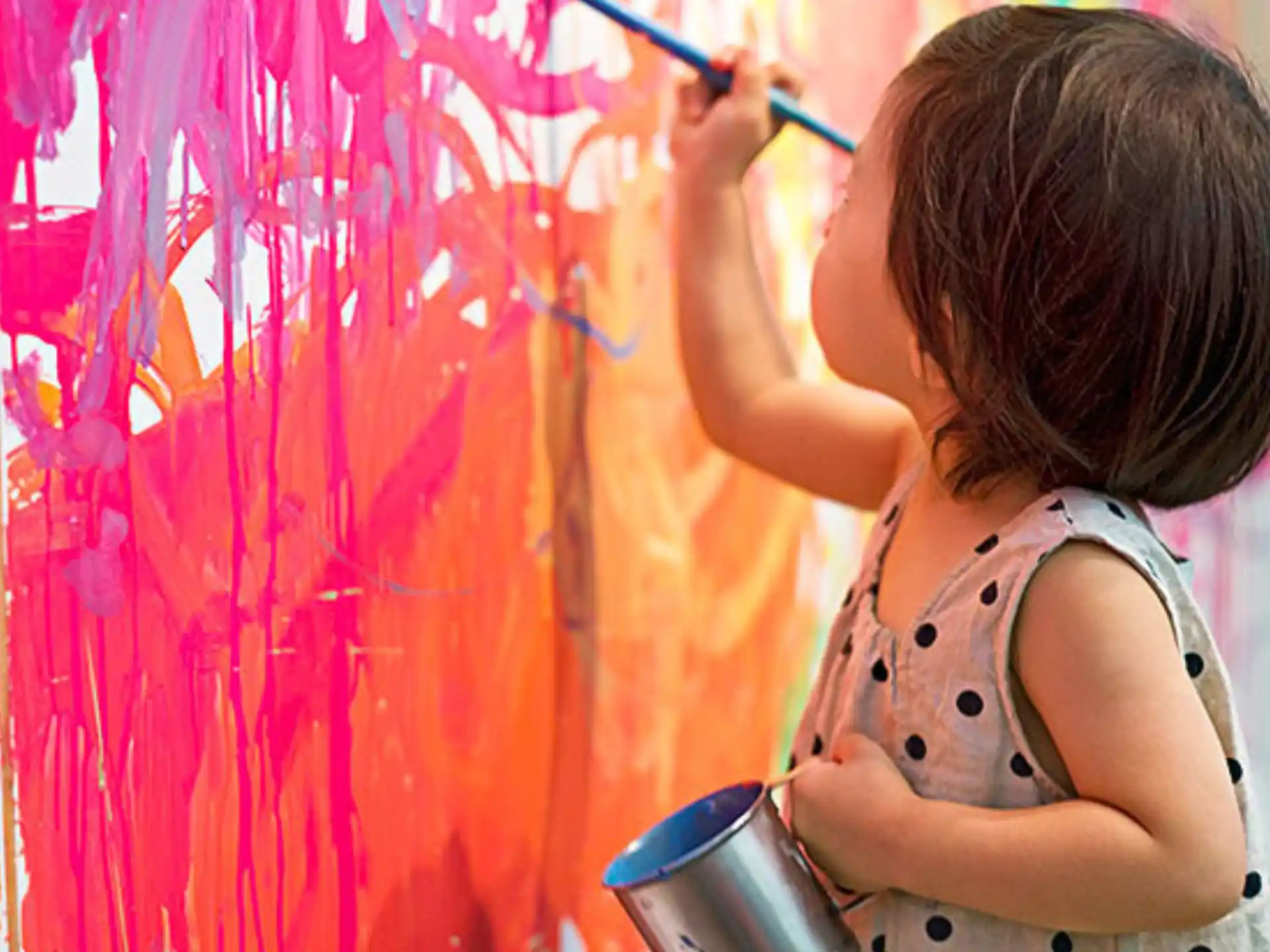 a young girl painting a wall