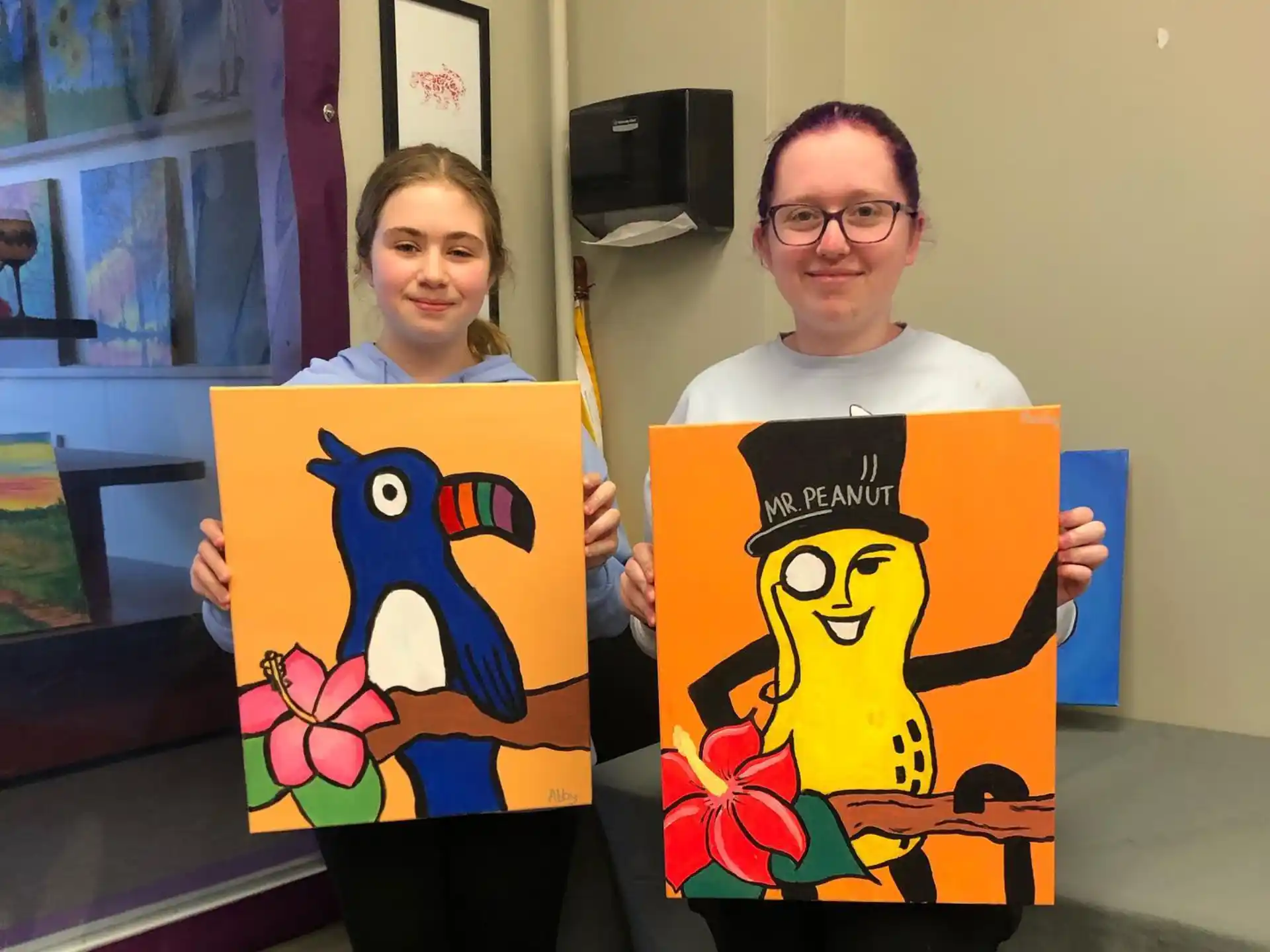 a man and a woman holding paintings