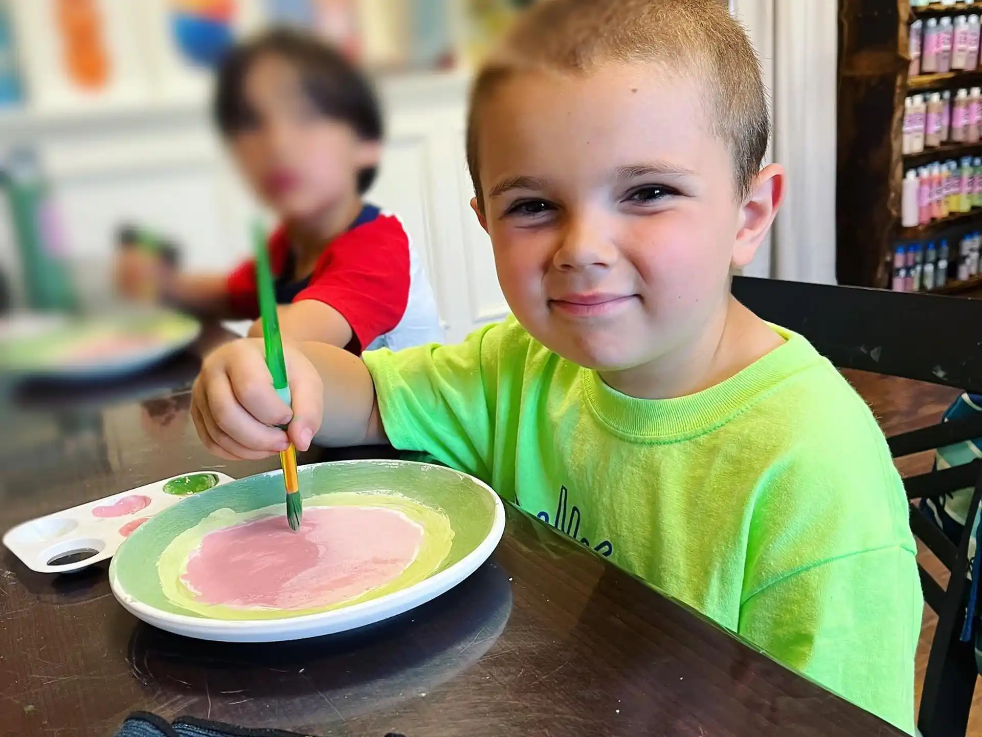 a boy sitting at a table with a plate of food