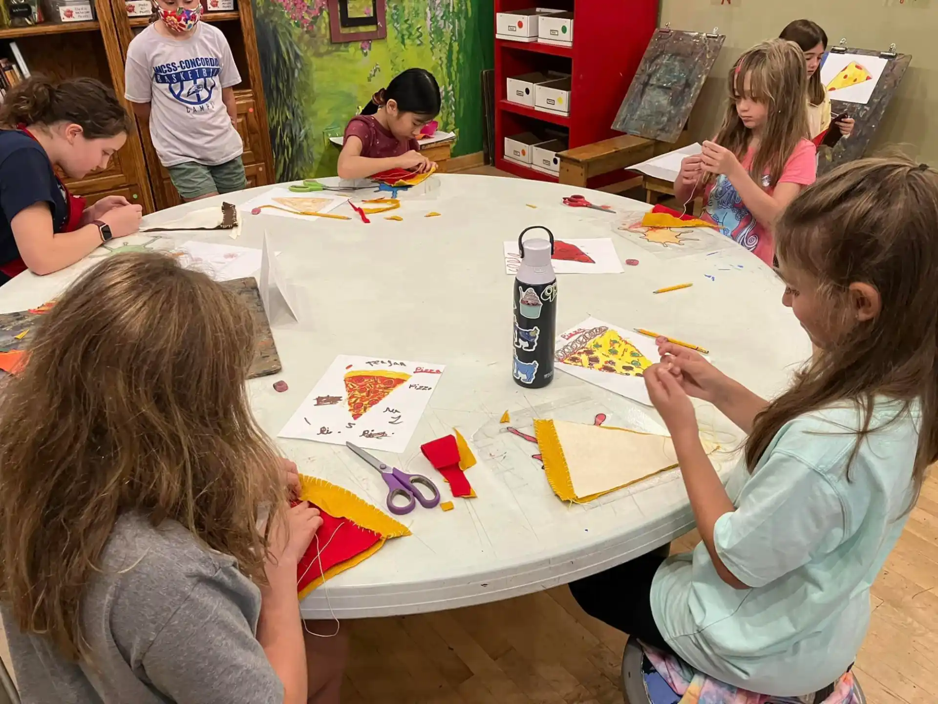 a group of children sitting around a table painting