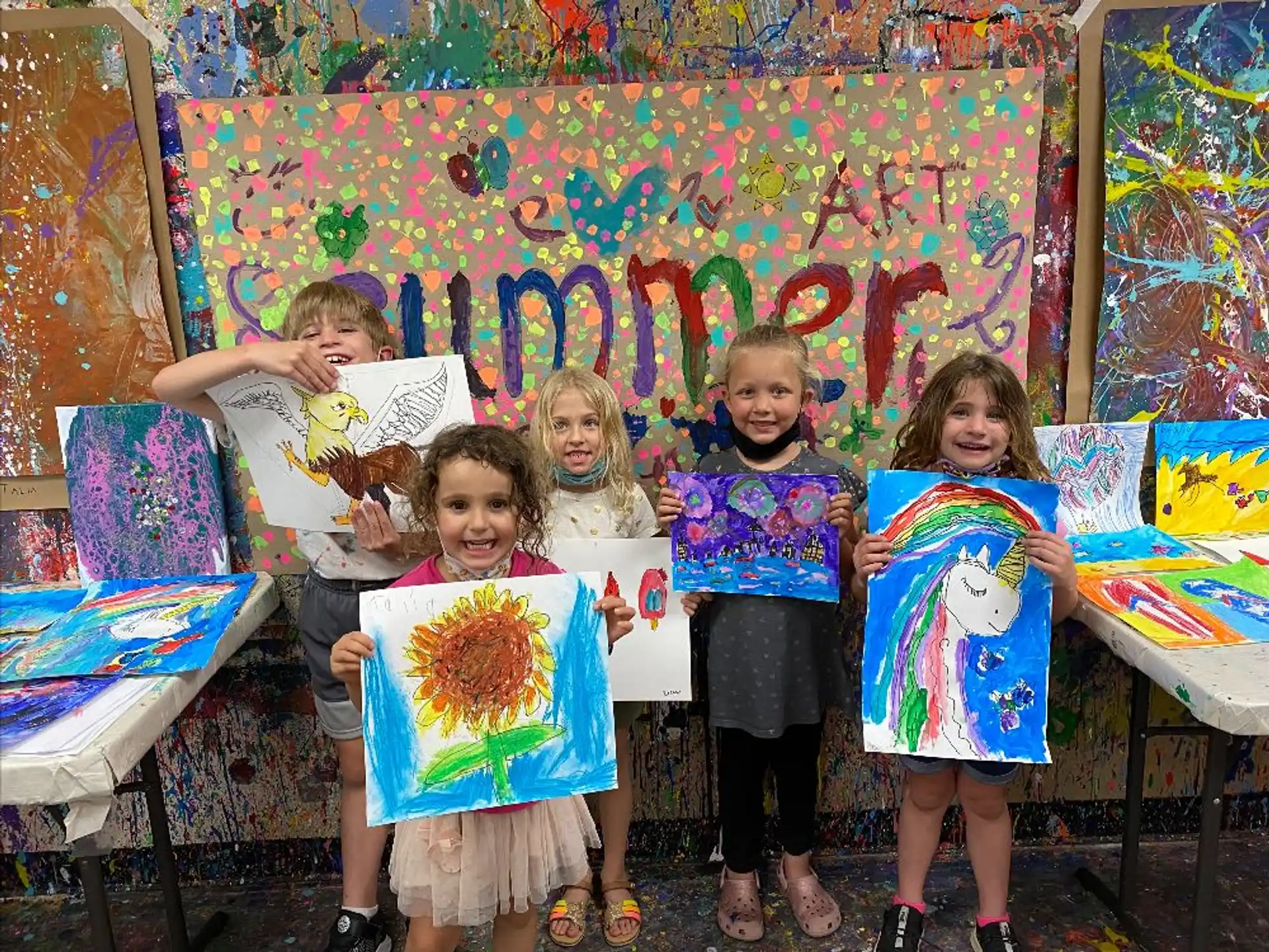 a group of children holding up paintings