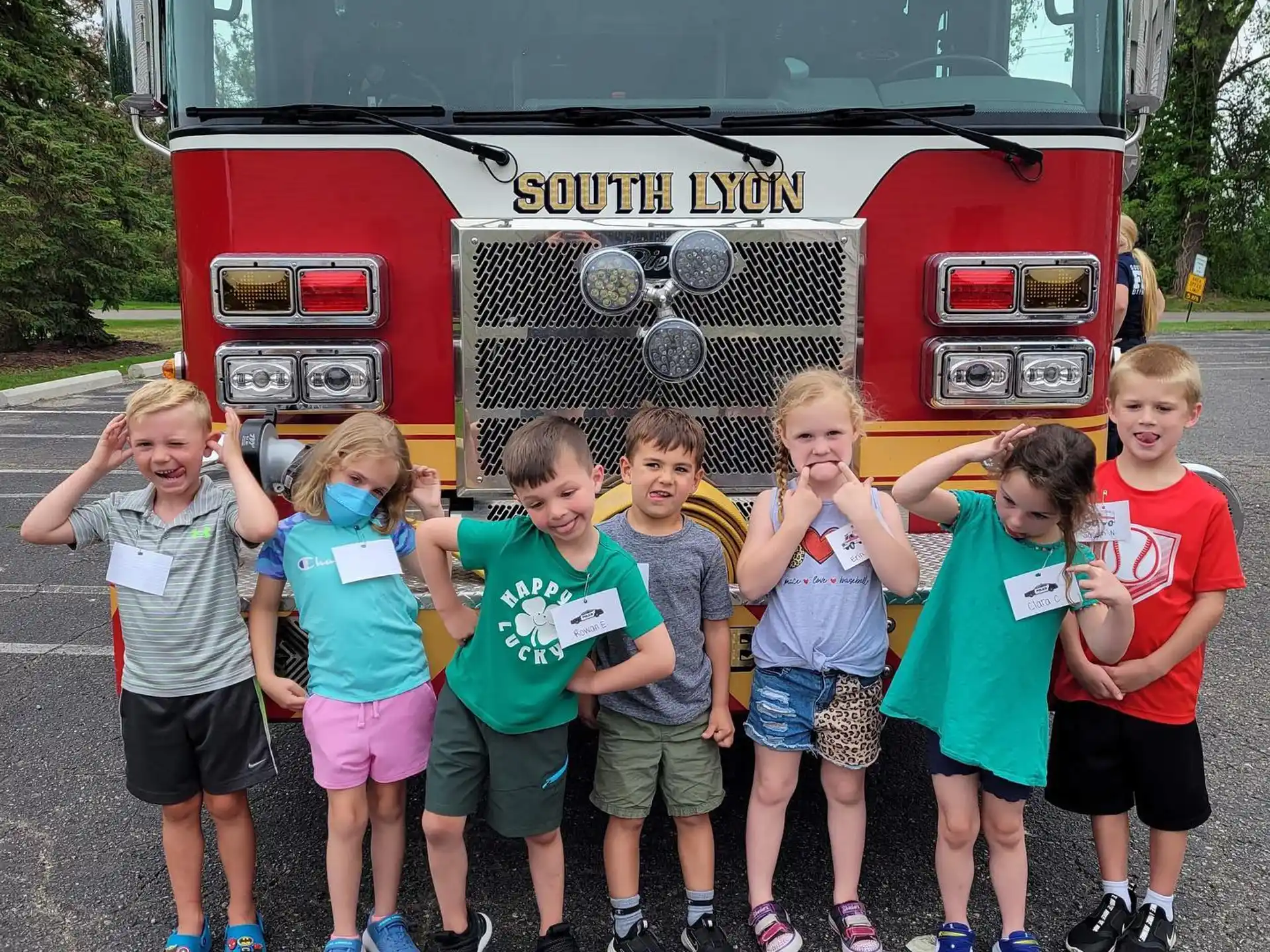 a group of children posing for a photo in front of a fire truck