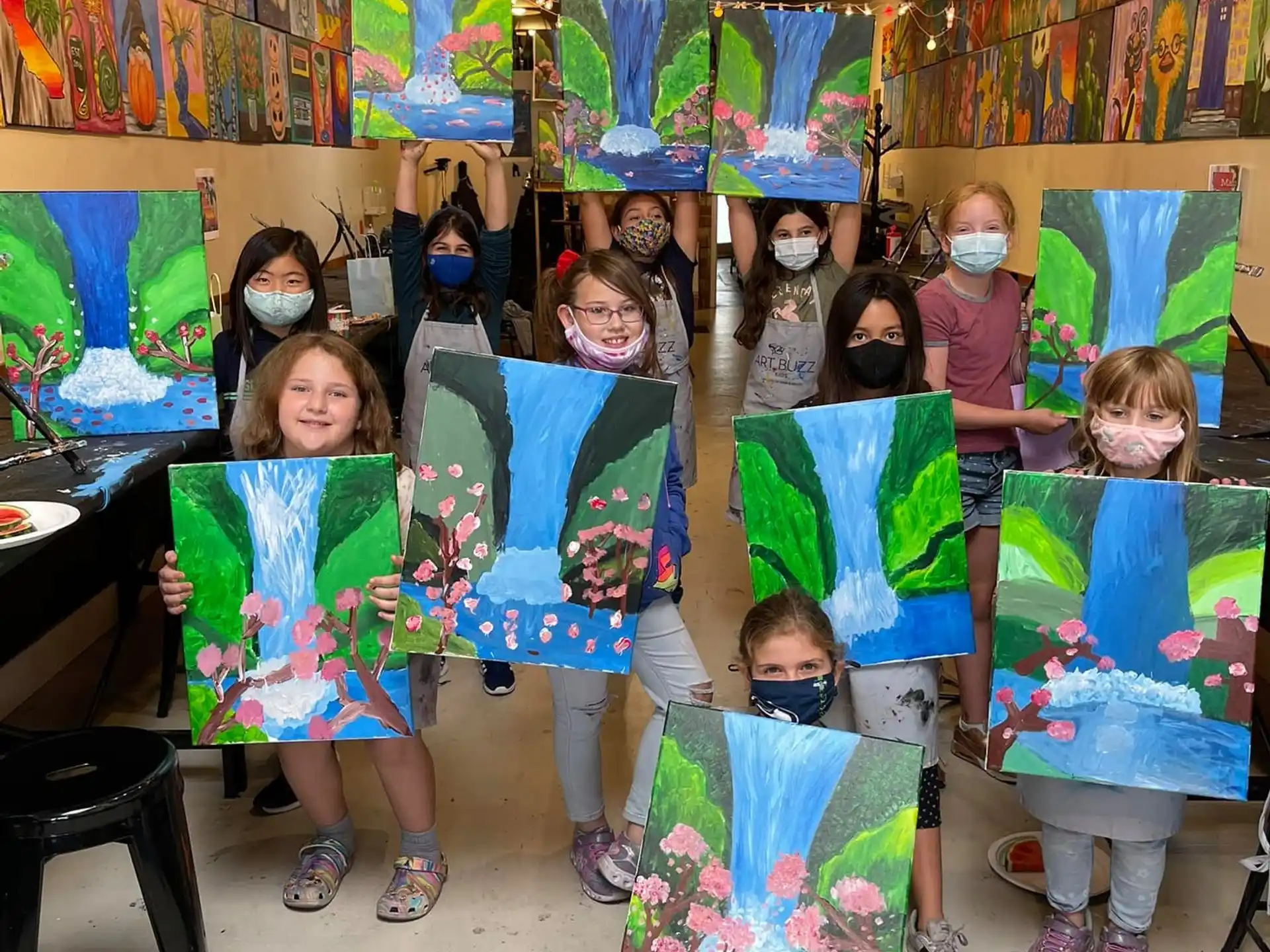 a group of children holding up paintings
