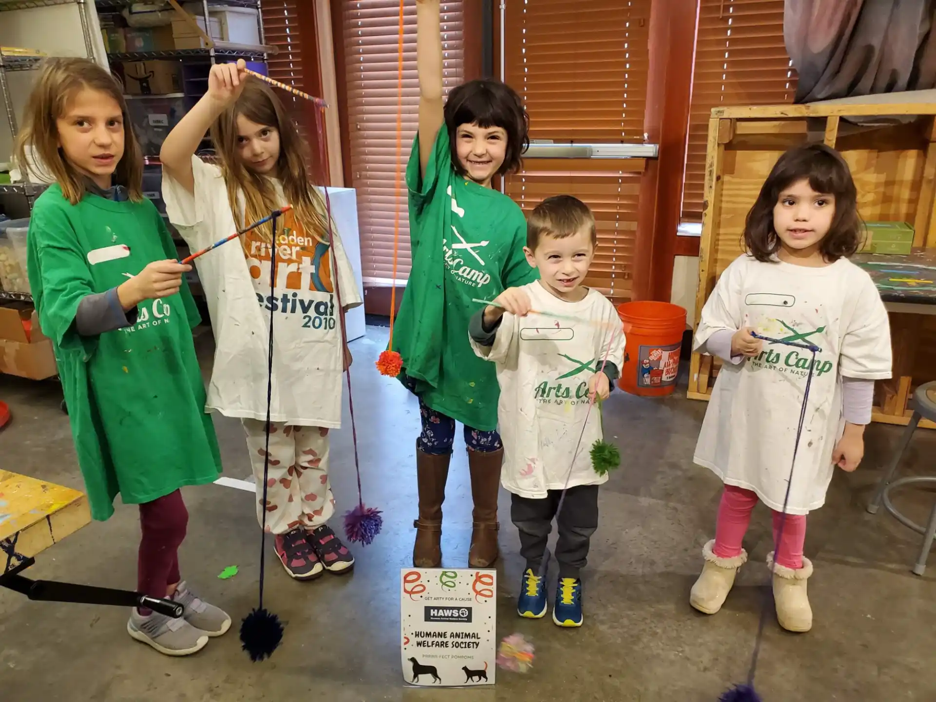 a group of children in green and white clothes holding objects