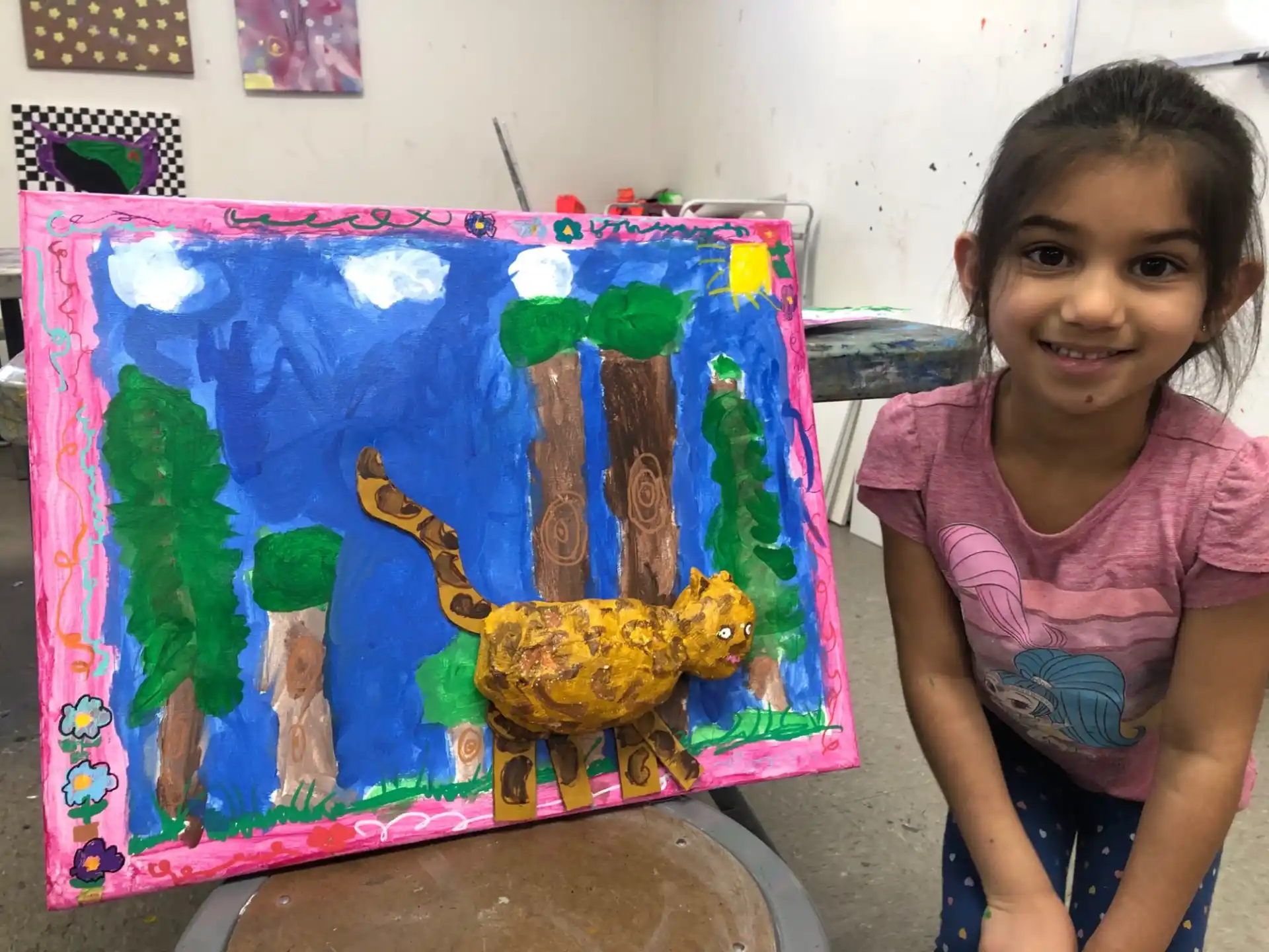 a girl sitting next to a painting
