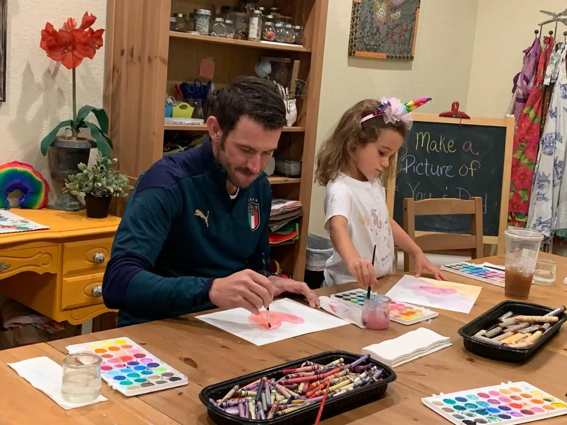 a person and a girl sitting at a table with a book and a book