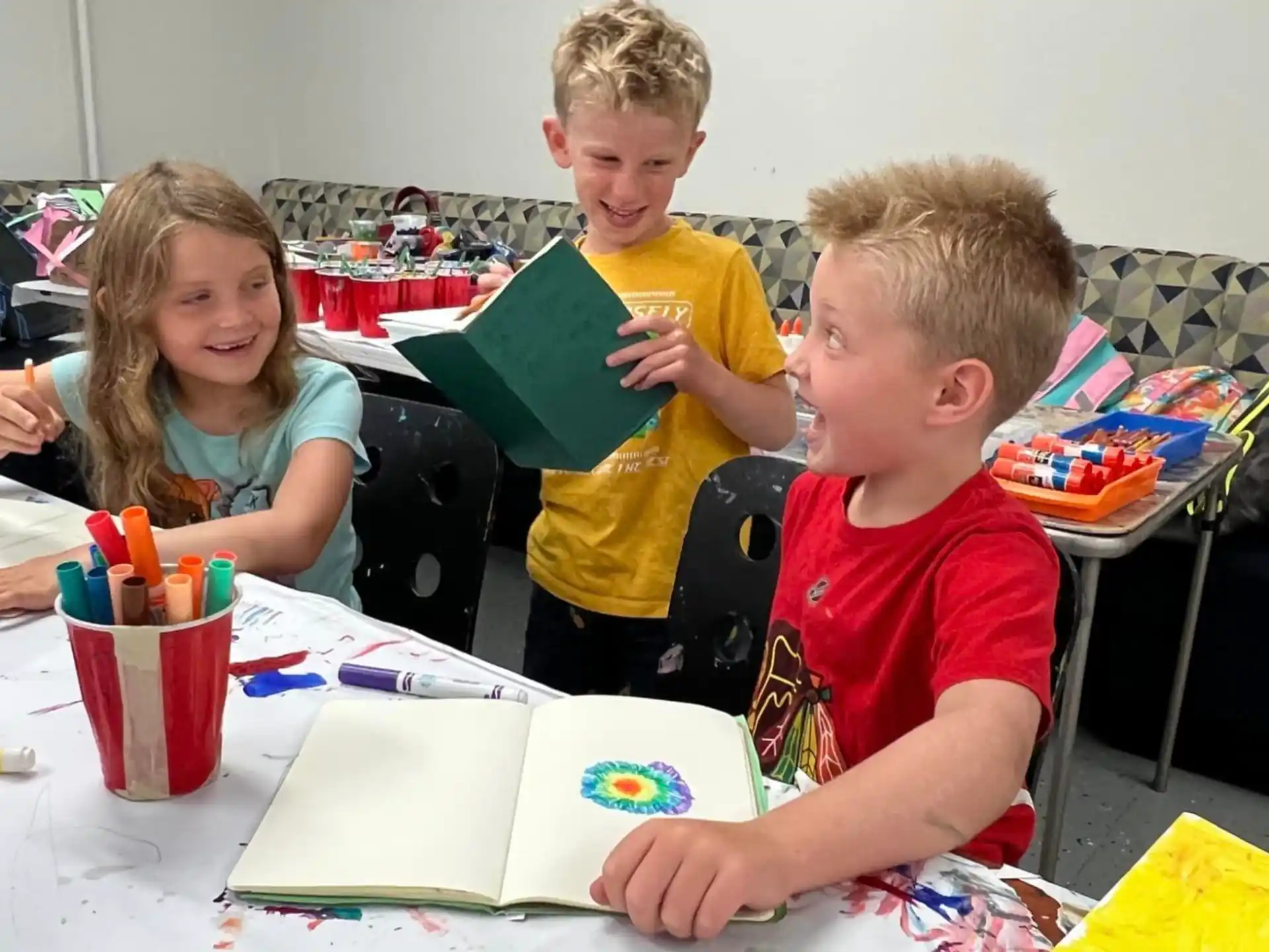 a group of children sitting at a table looking at a book