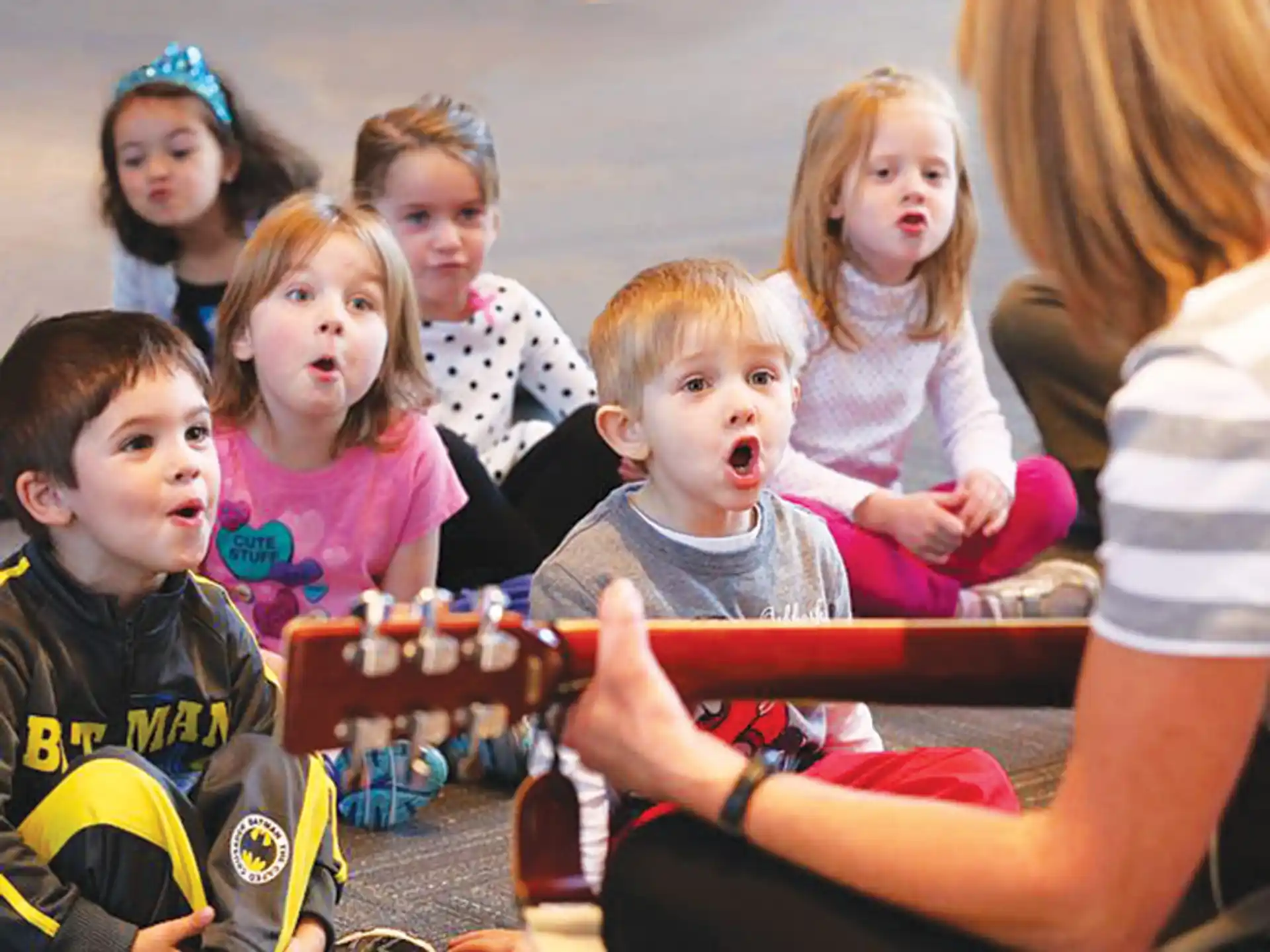a group of children sitting around a table with a cake