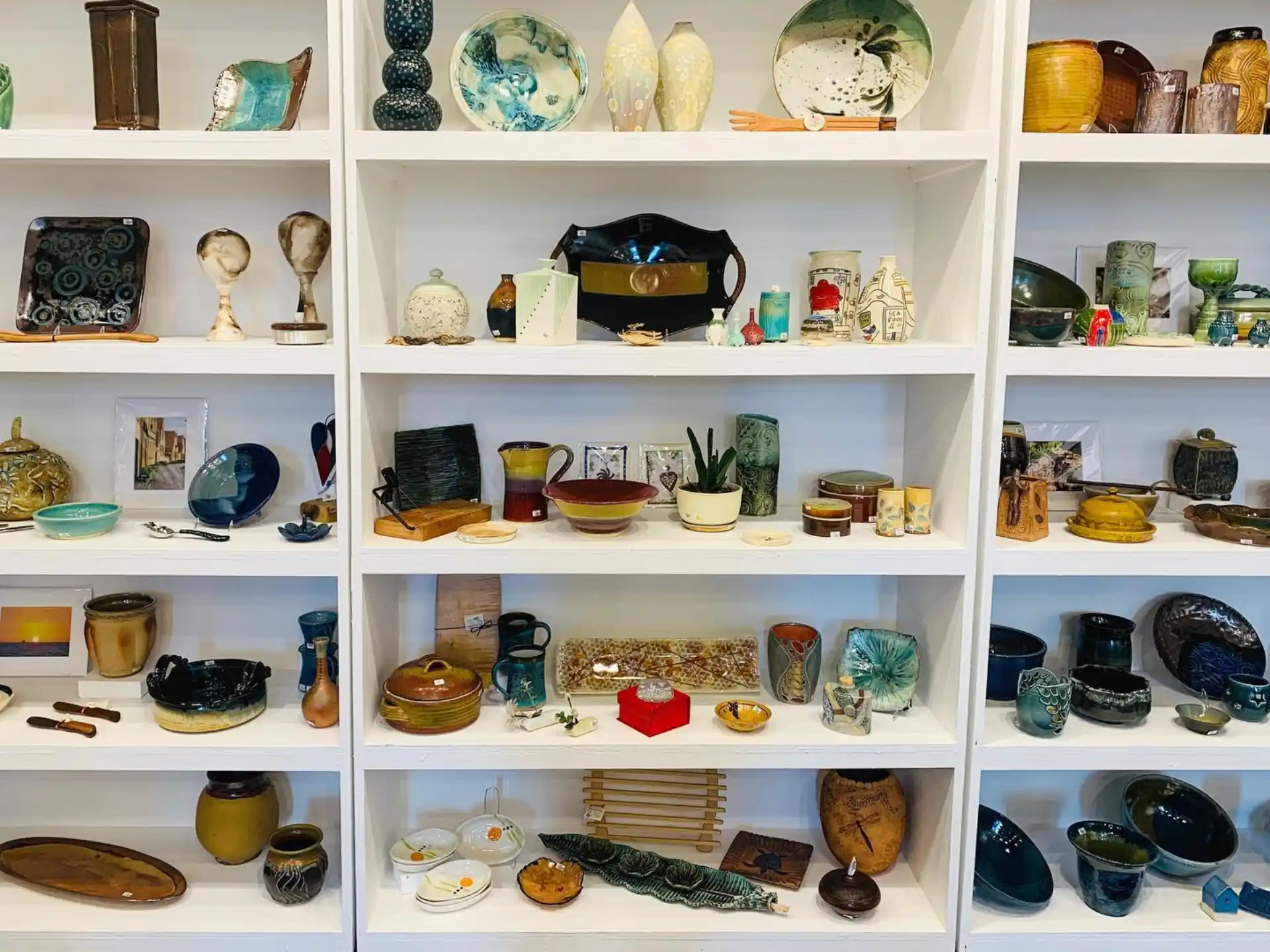 a shelf with many vases and bowls on it