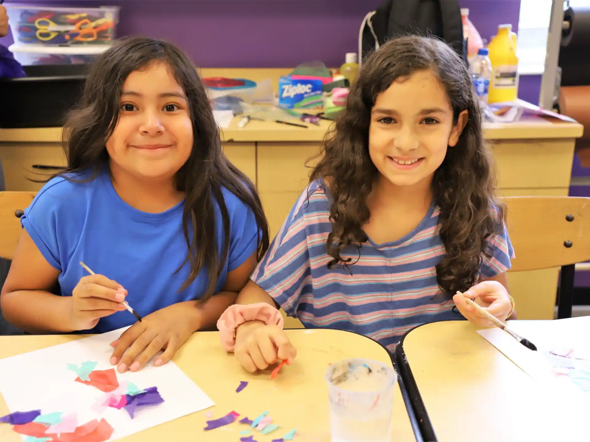 a couple of girls sitting at a table with a piece of paper
