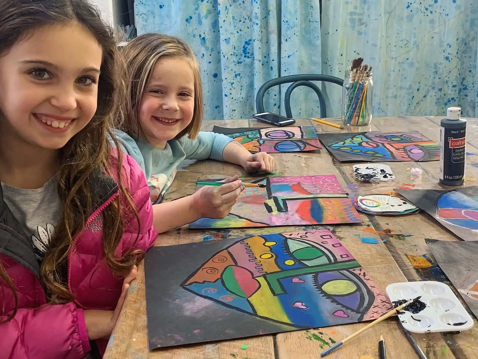 a couple of girls sitting at a table with a board game