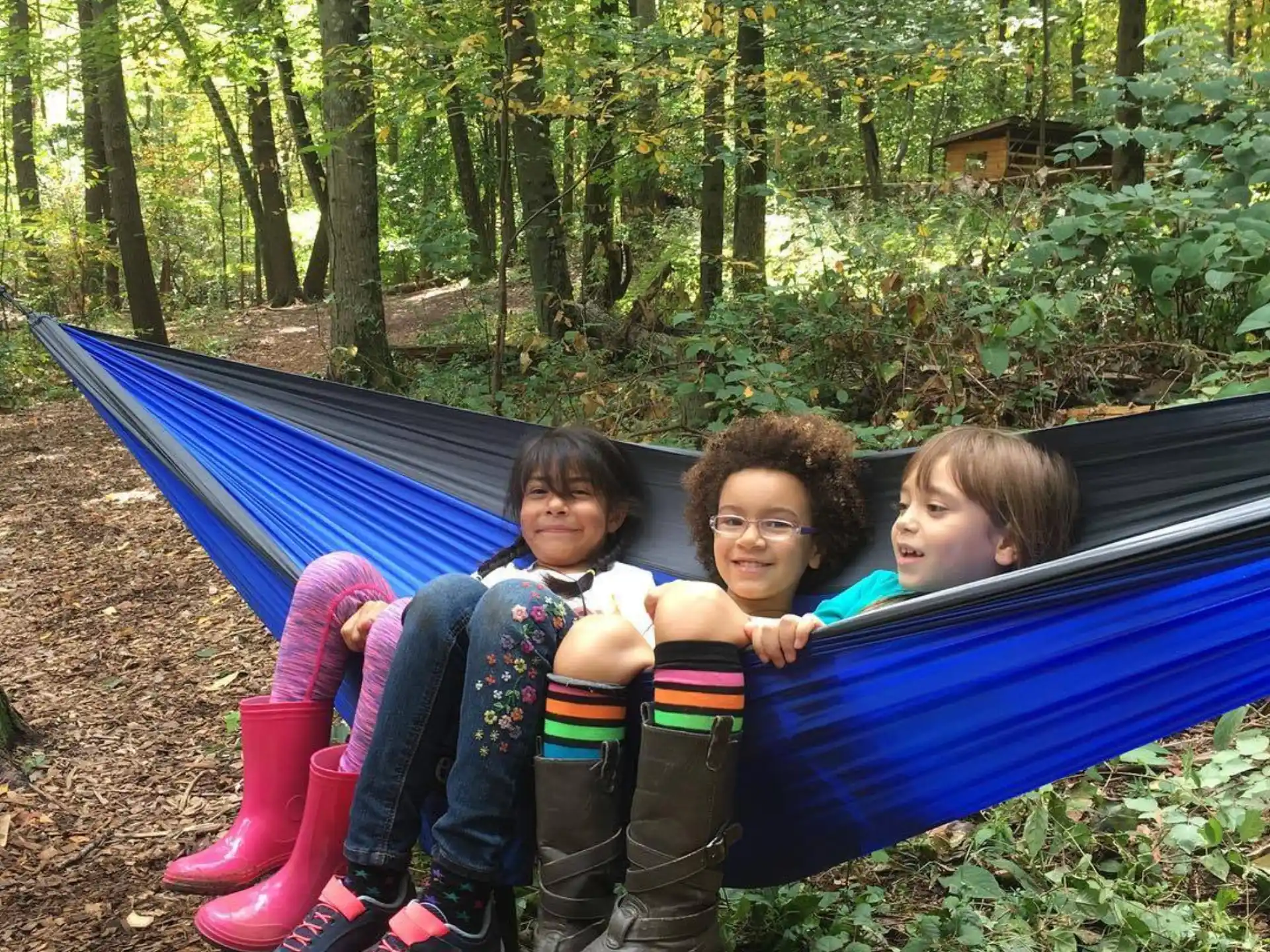 a group of children sitting on a blue slide in a forest