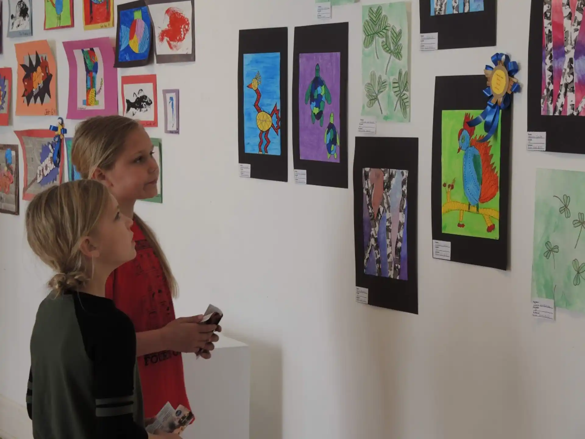 a couple of women looking at a wall of art