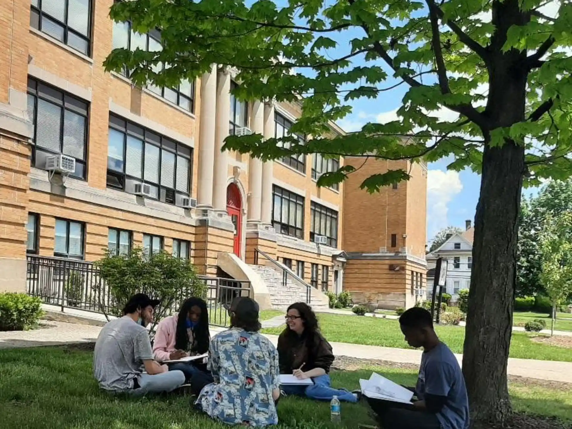 a group of people sitting on the grass in front of a building