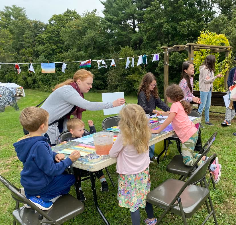 a person and children sitting at a table with food and drinks