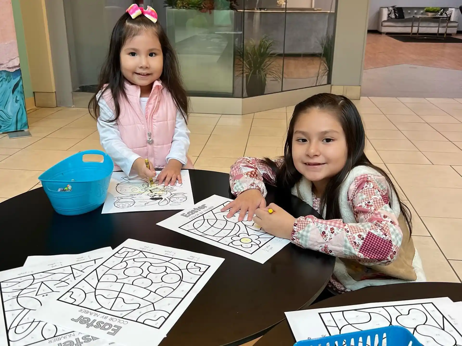 a couple of girls sitting at a table with drawings on it