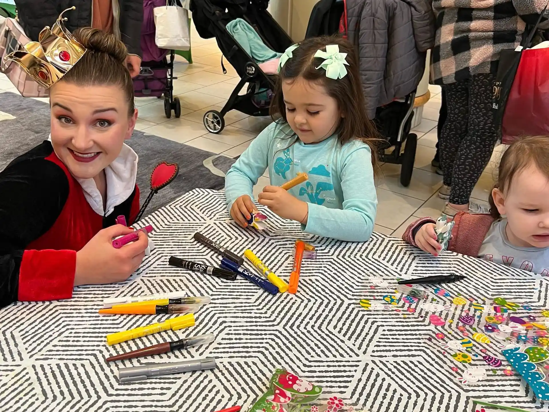 a group of children sitting at a table with craft supplies