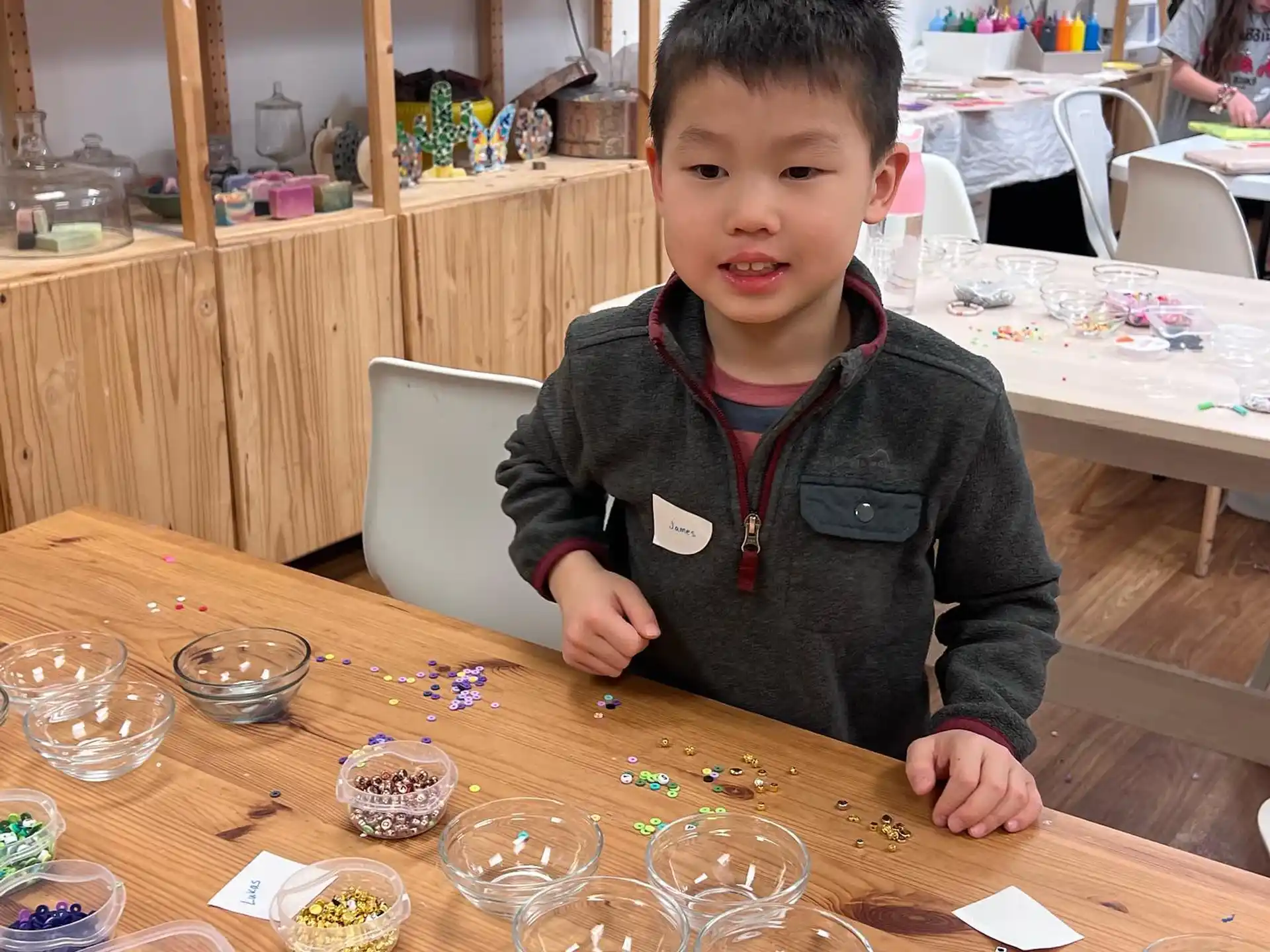 a boy sitting at a table with many glasses and food