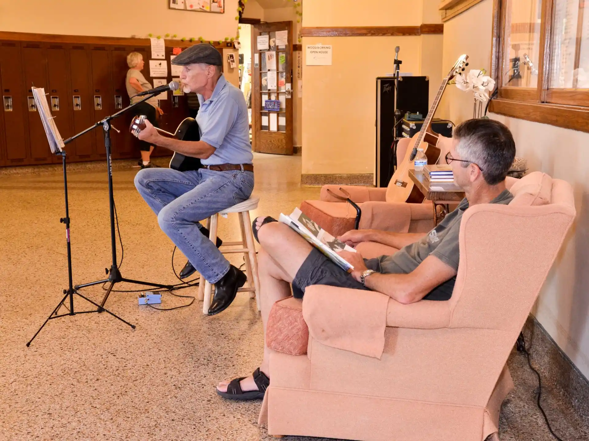 a person playing guitar next to a person sitting on a couch