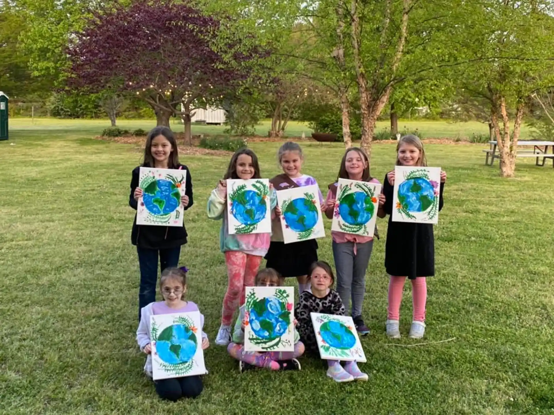 a group of children holding up colorful bags in a grassy area