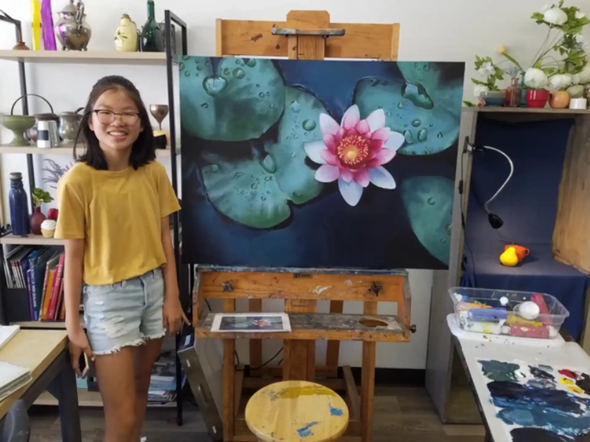 a girl standing next to a painting