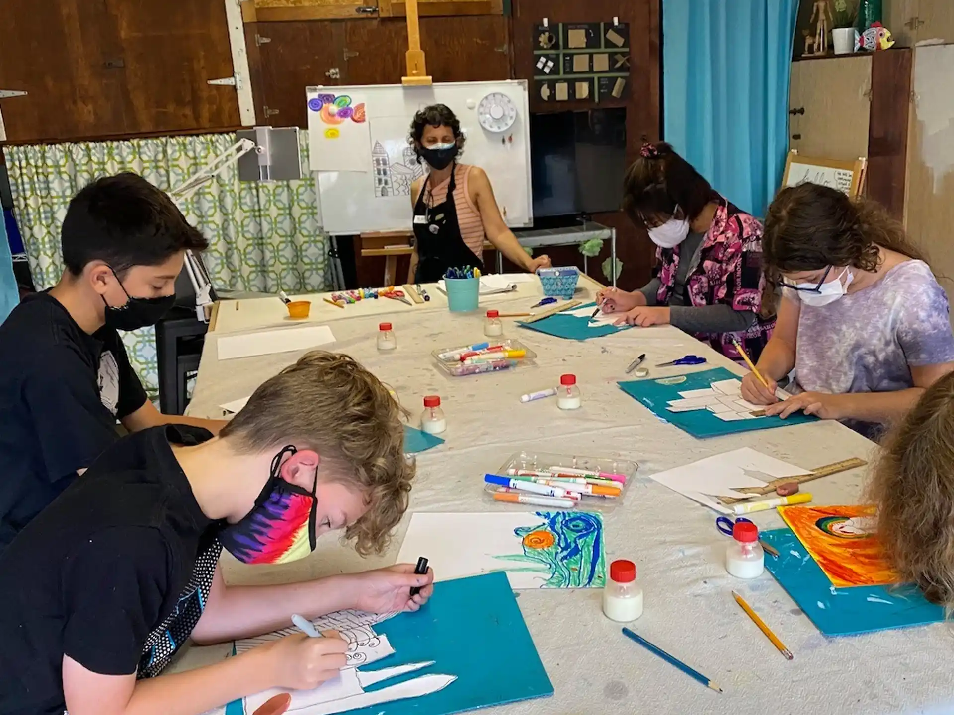 a group of people sitting around a table with colored pencils