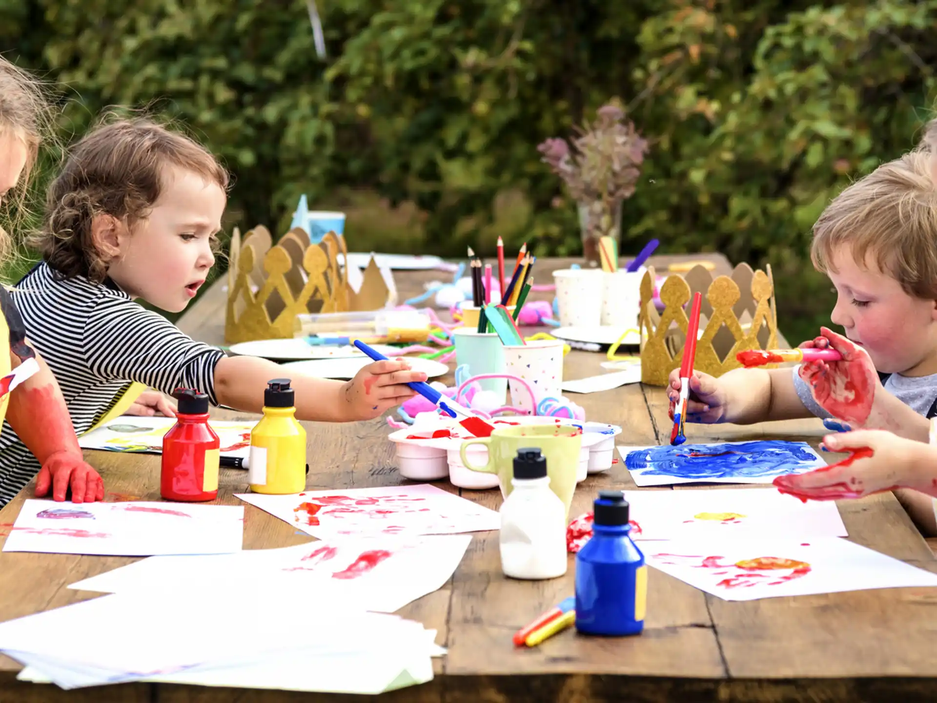 a group of children sitting at a table with a paper and pencils