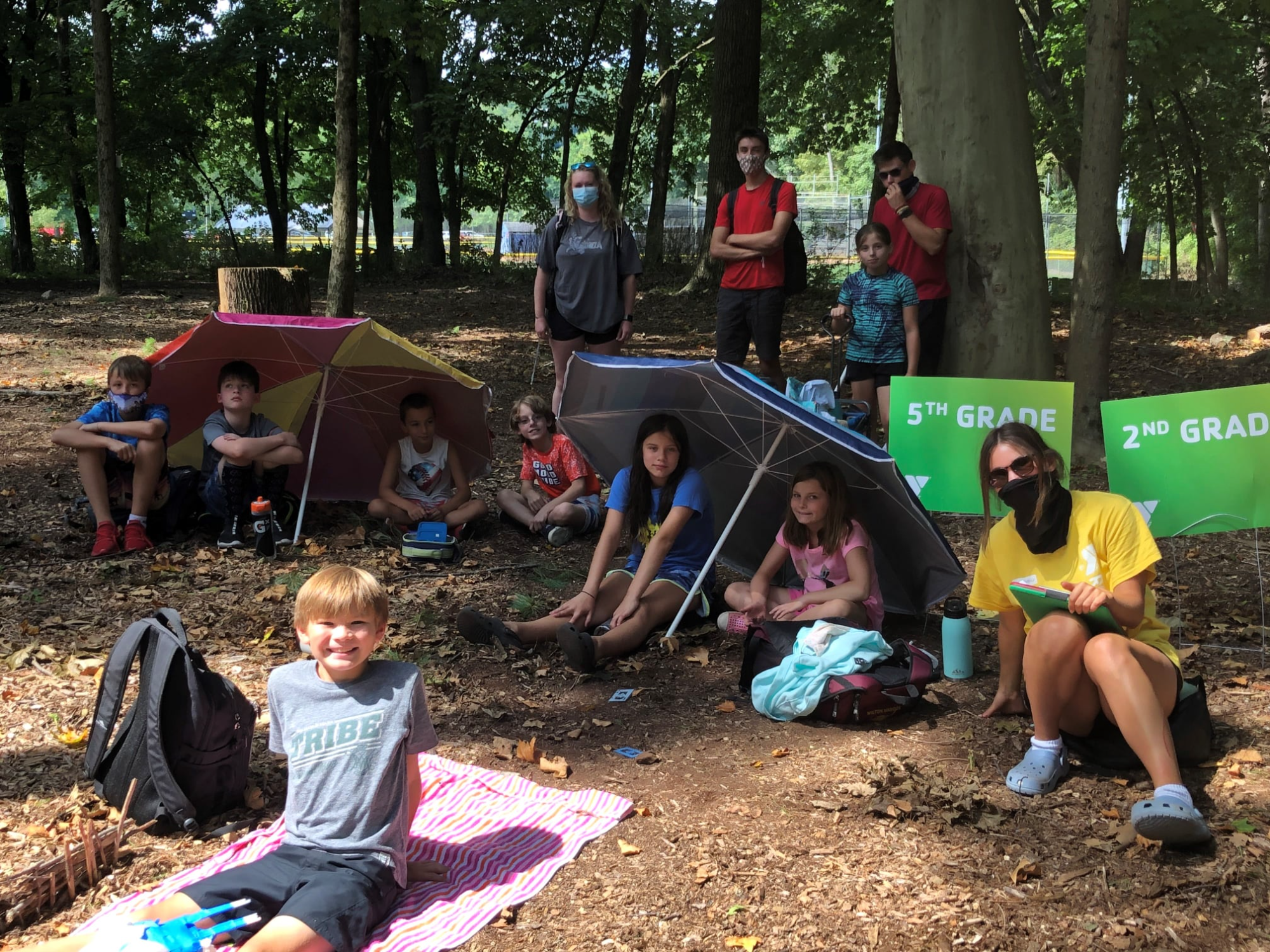 a group of people sitting around a tent in a forest