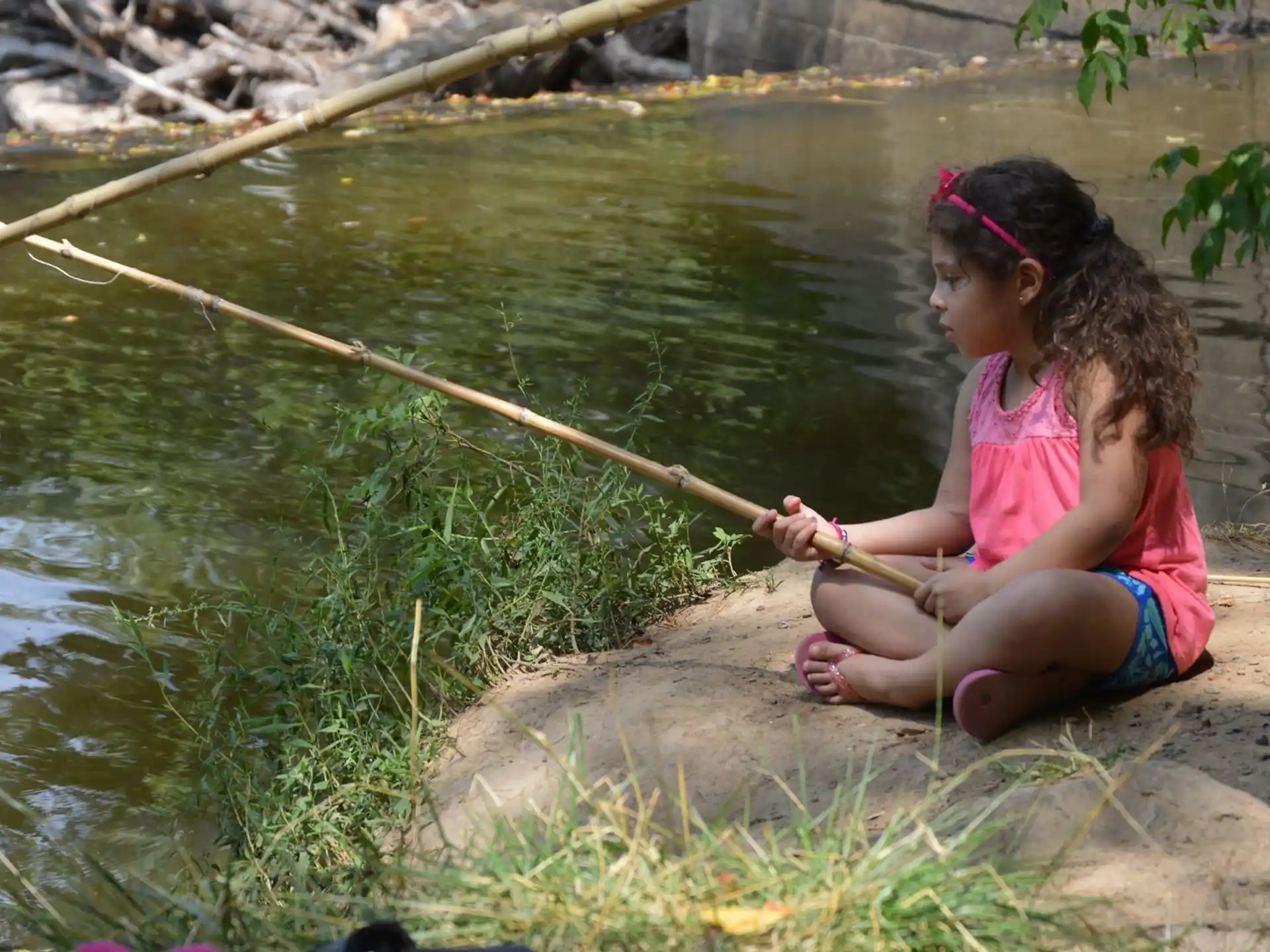 a girl sitting on a rock next to a body of water