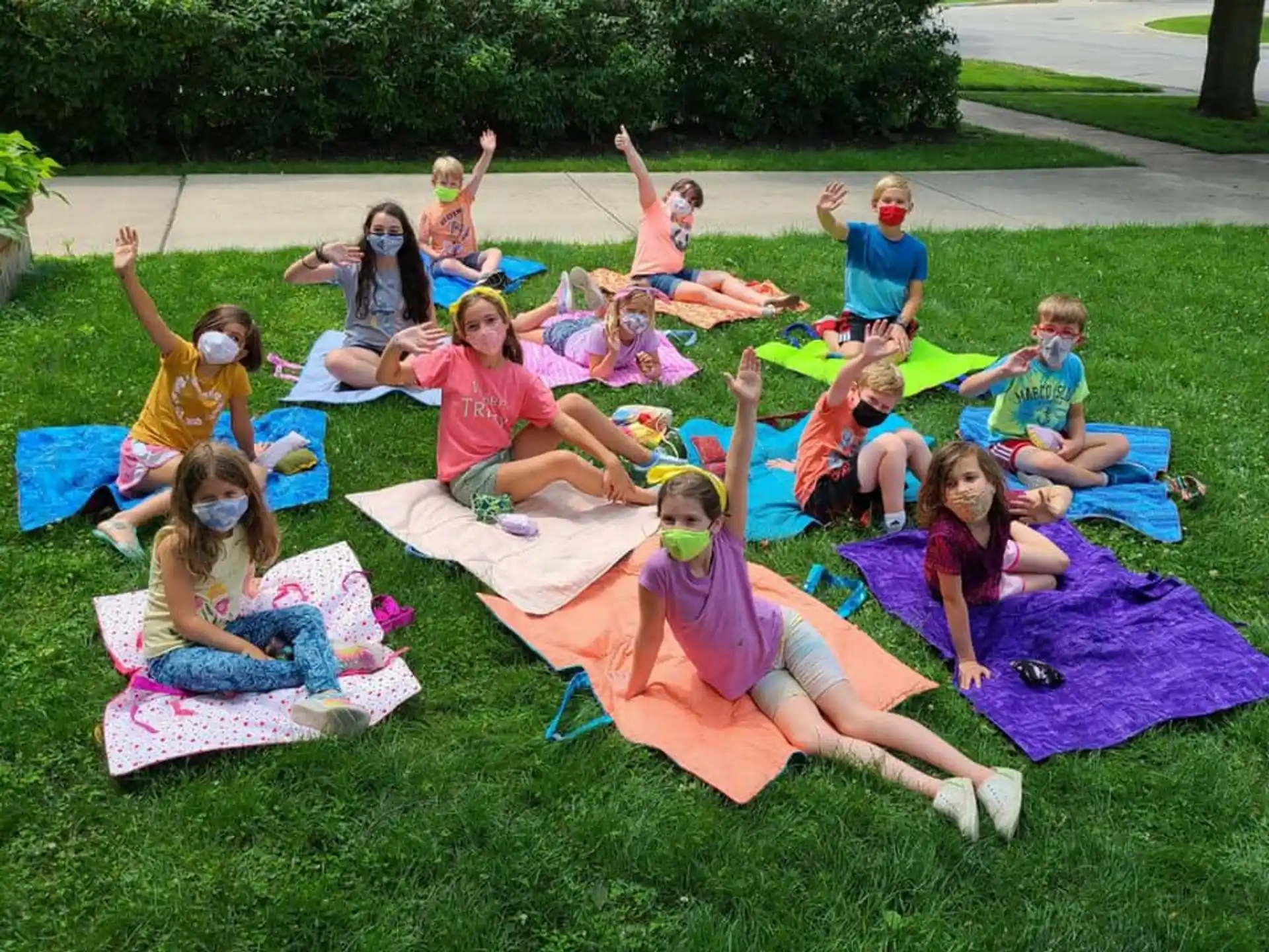 a group of people sitting on mats in a grassy area