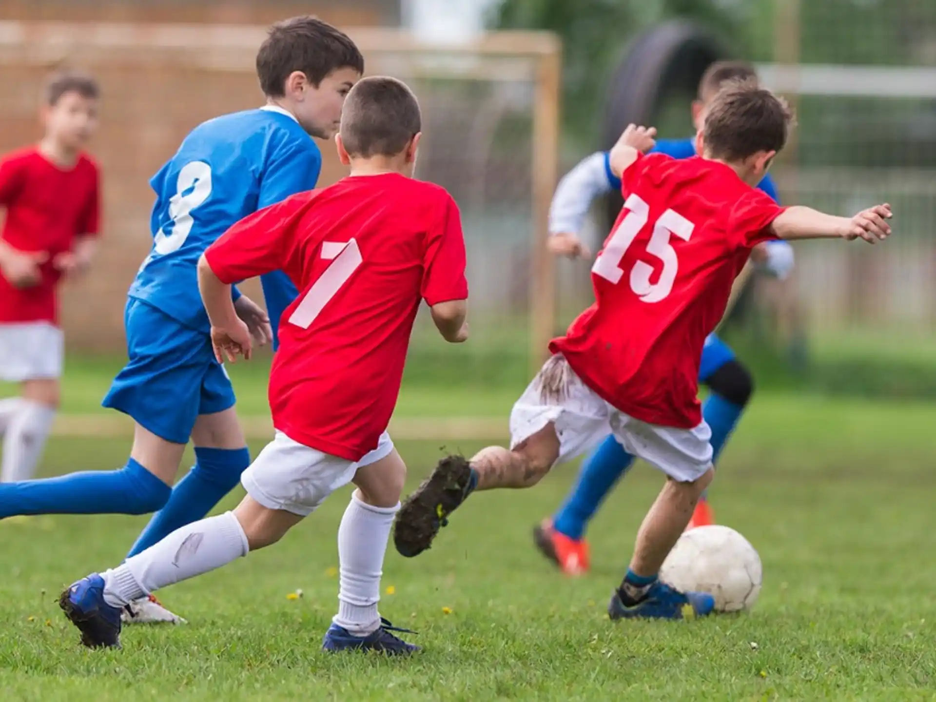 a group of boys compete over a football ball