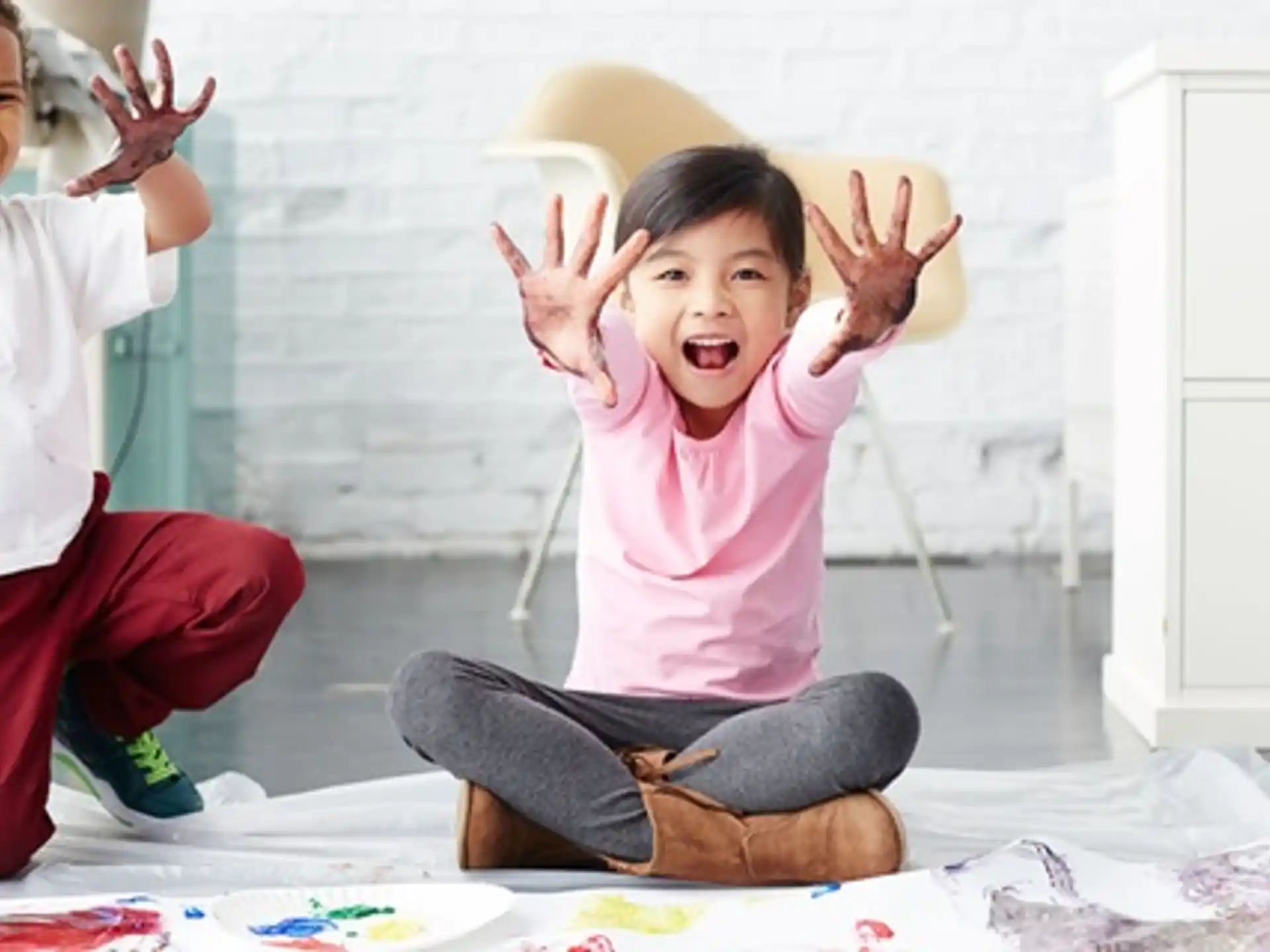a couple of kids sitting on the floor with their hands up